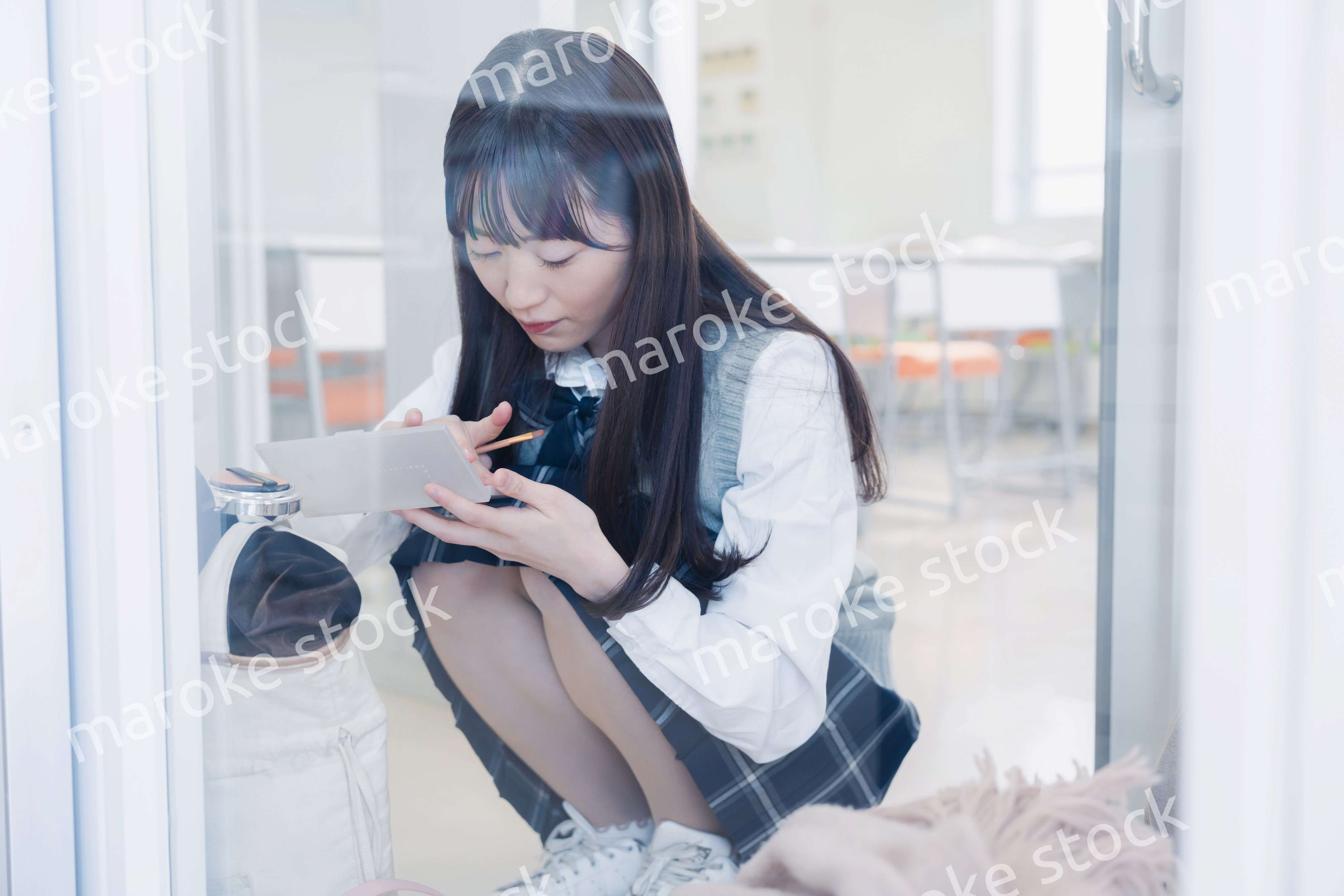 学校でメイクをする女子高生