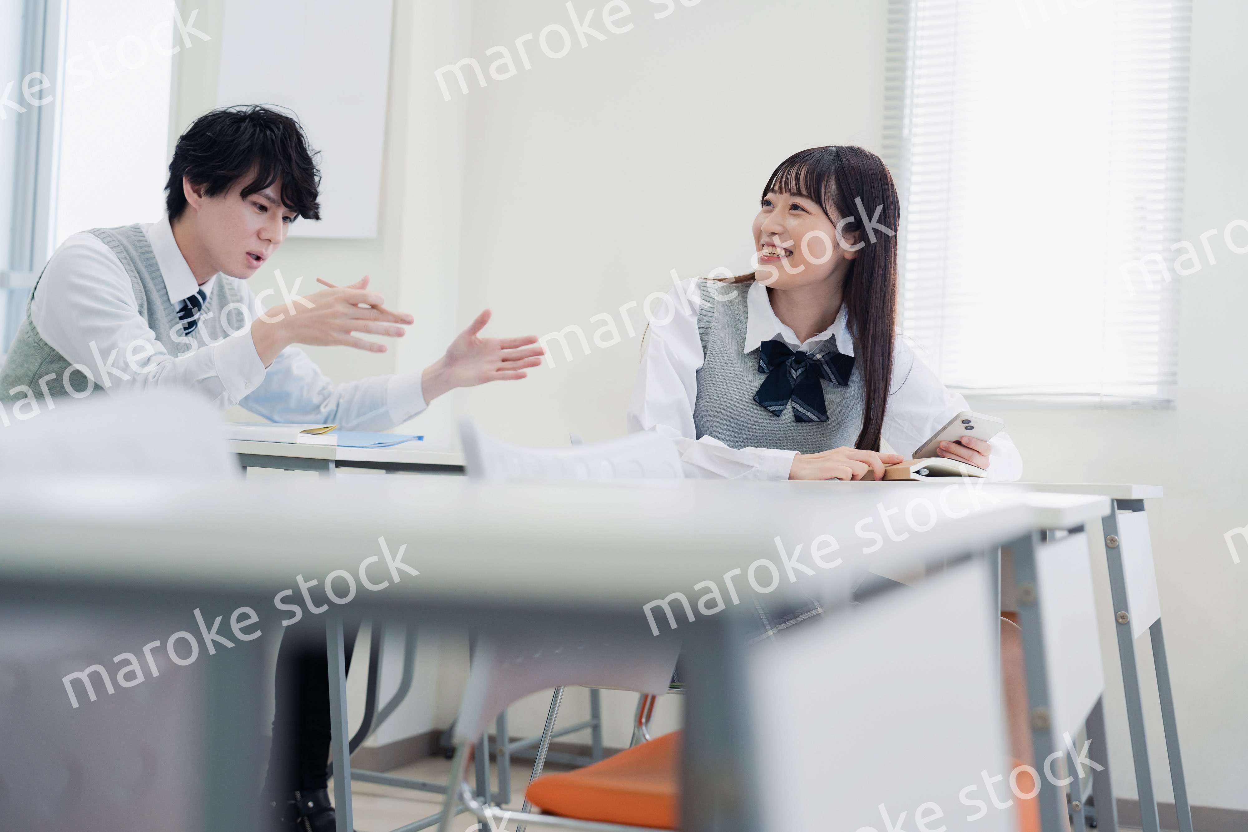 同級生と教室で仲良く話す高校生