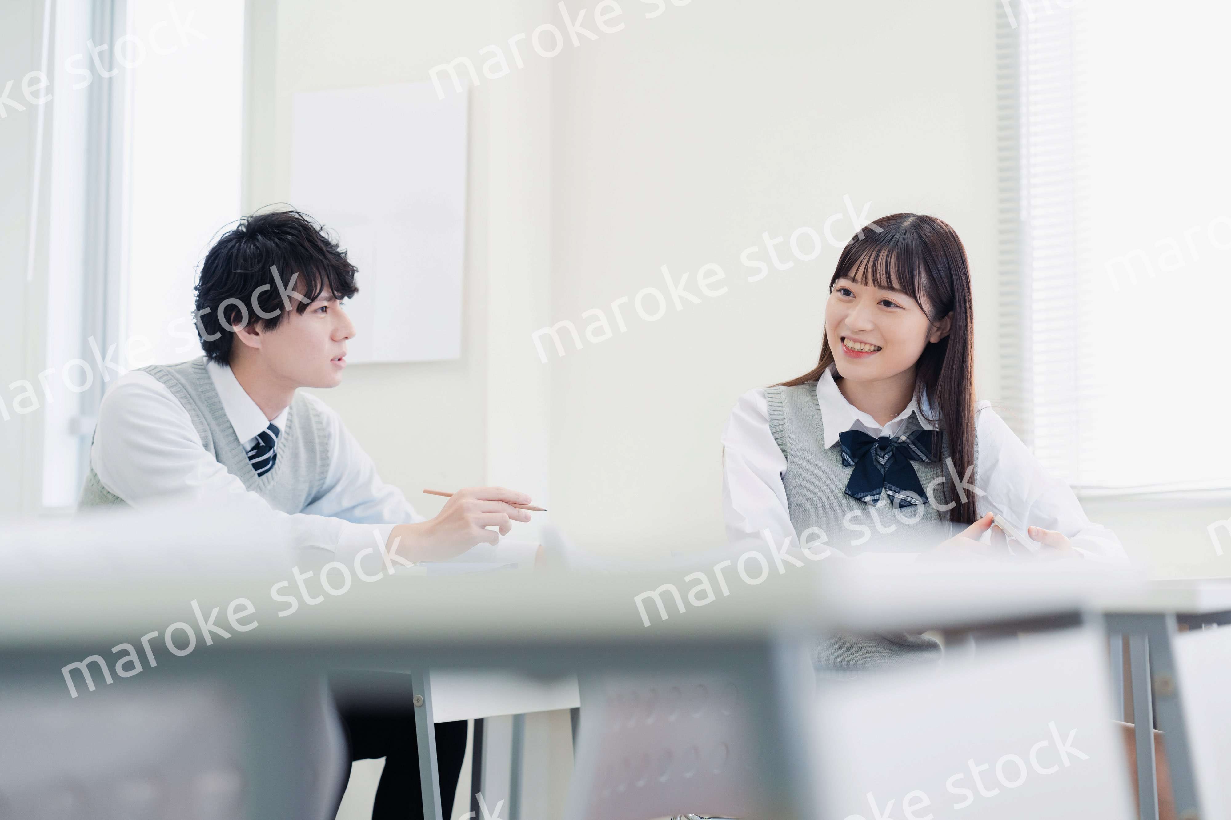 同級生と教室で仲良く話す高校生