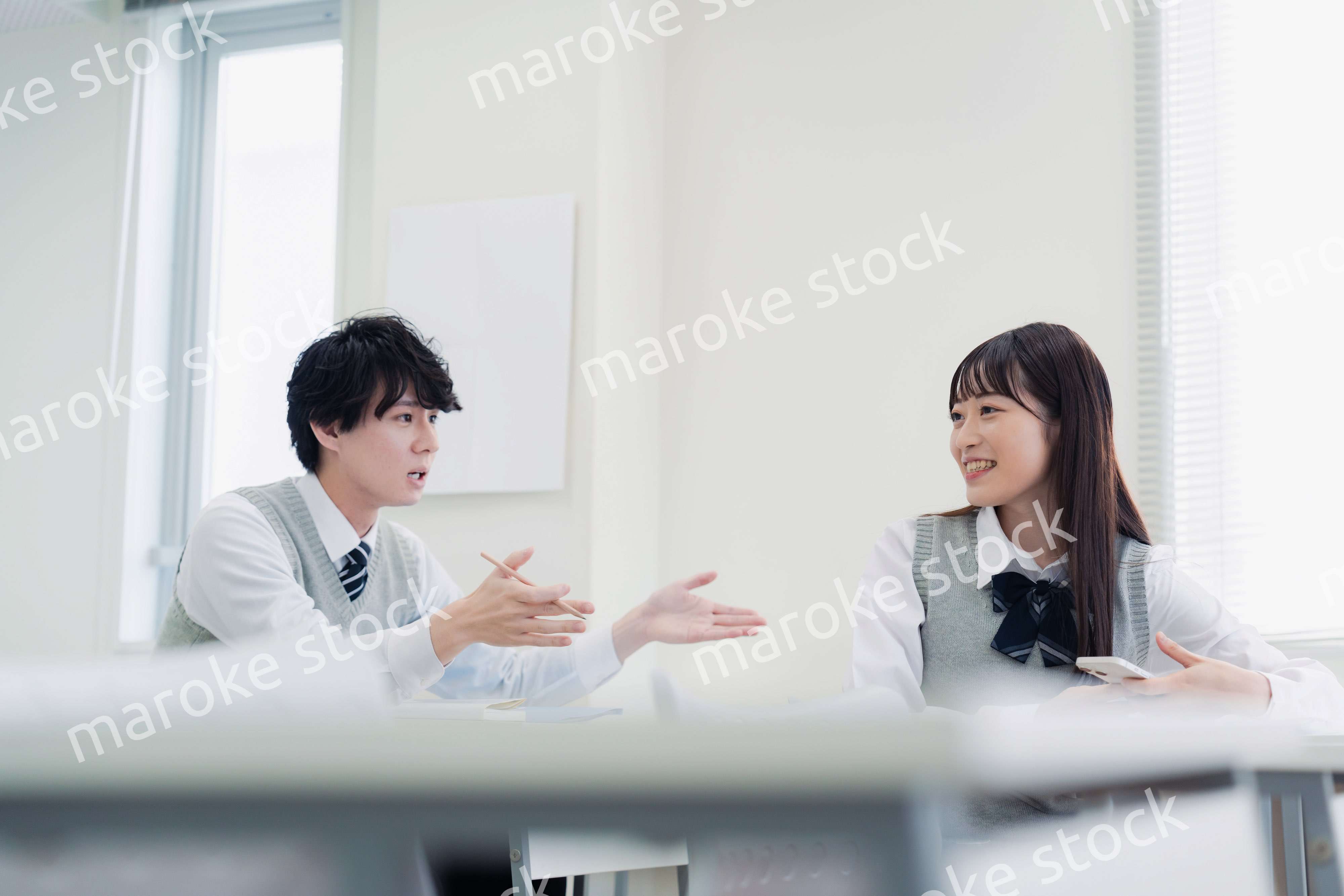 同級生と教室で仲良く話す高校生