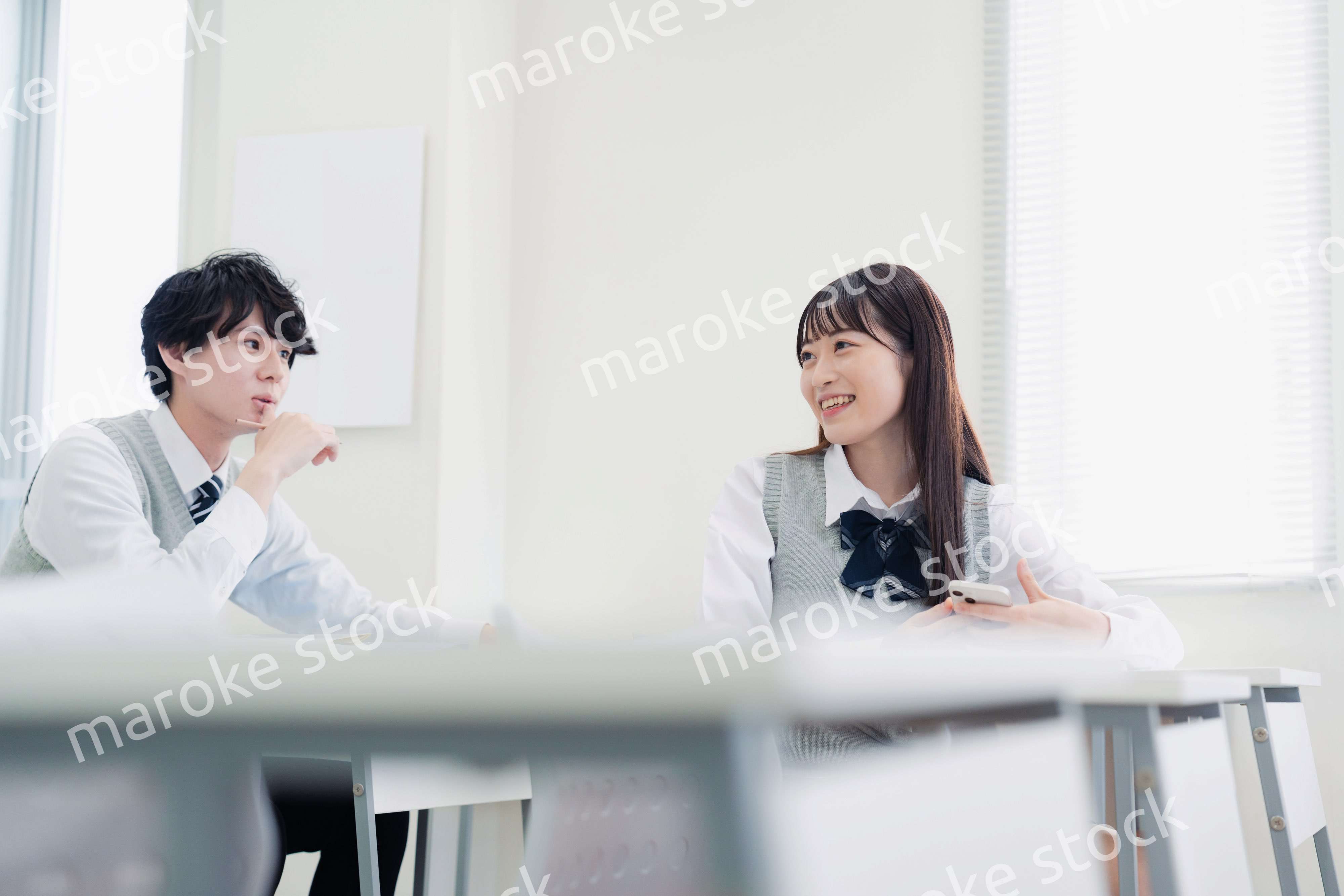 同級生と教室で仲良く話す高校生