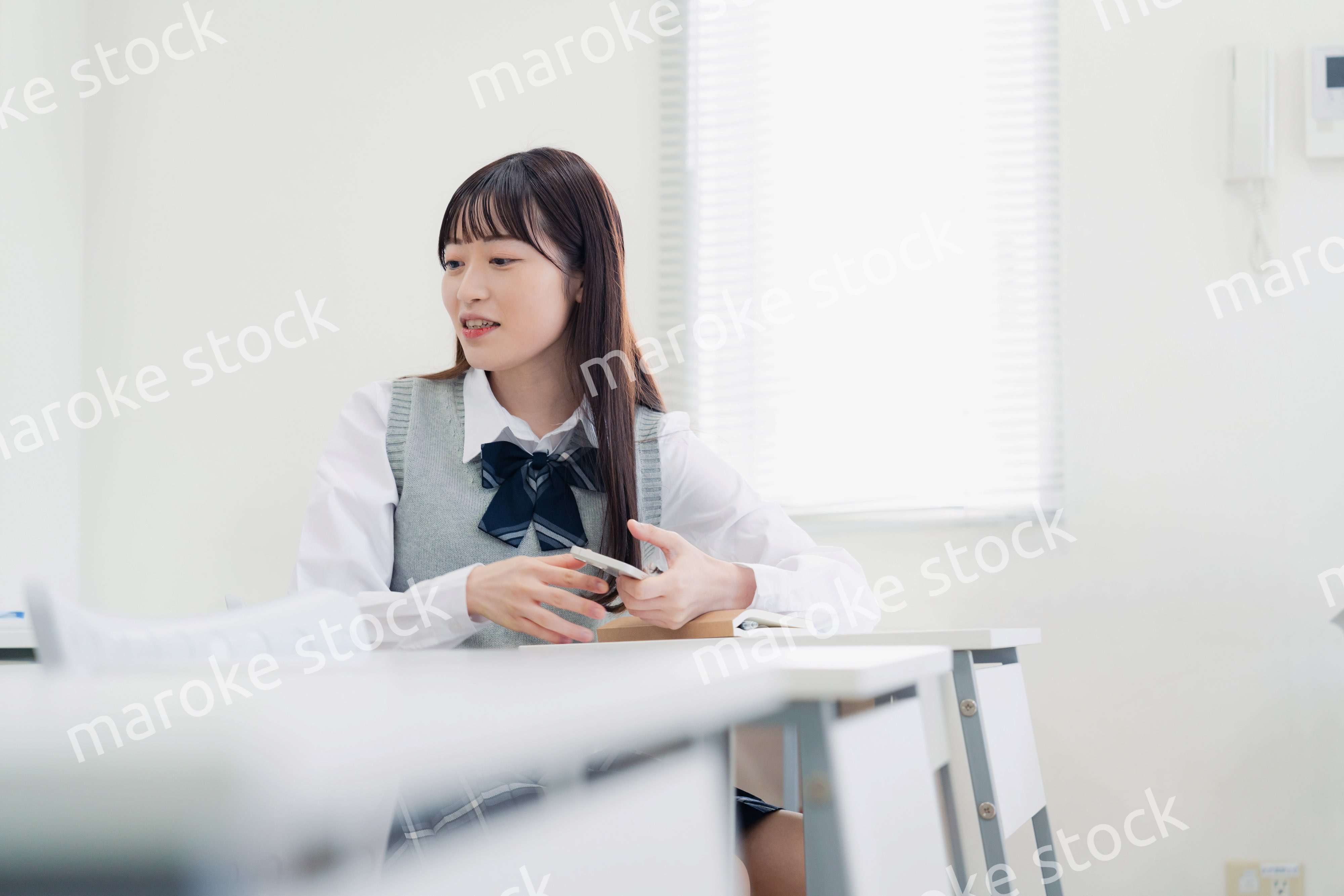 同級生と教室で仲良く話す高校生