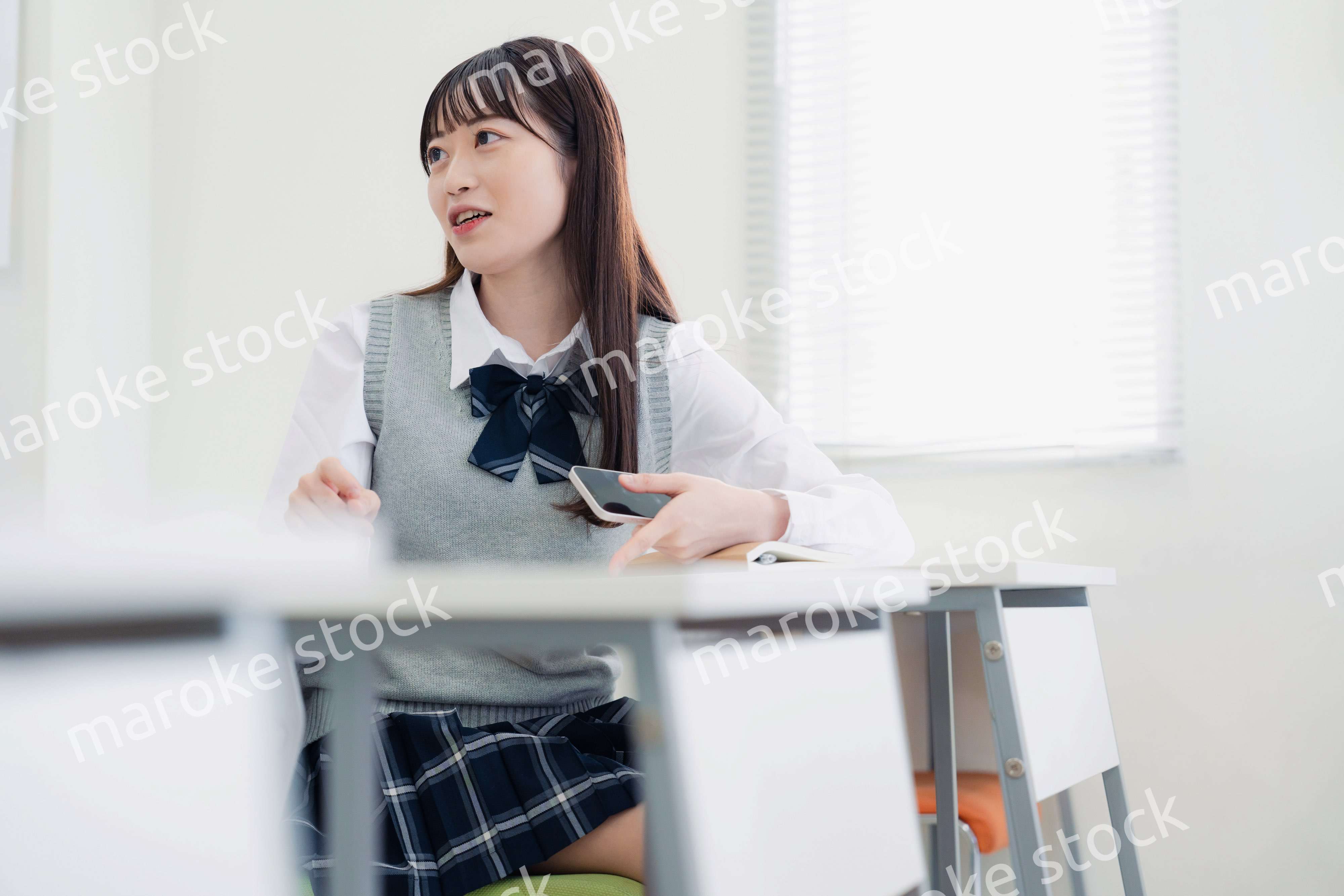 同級生と教室で仲良く話す高校生