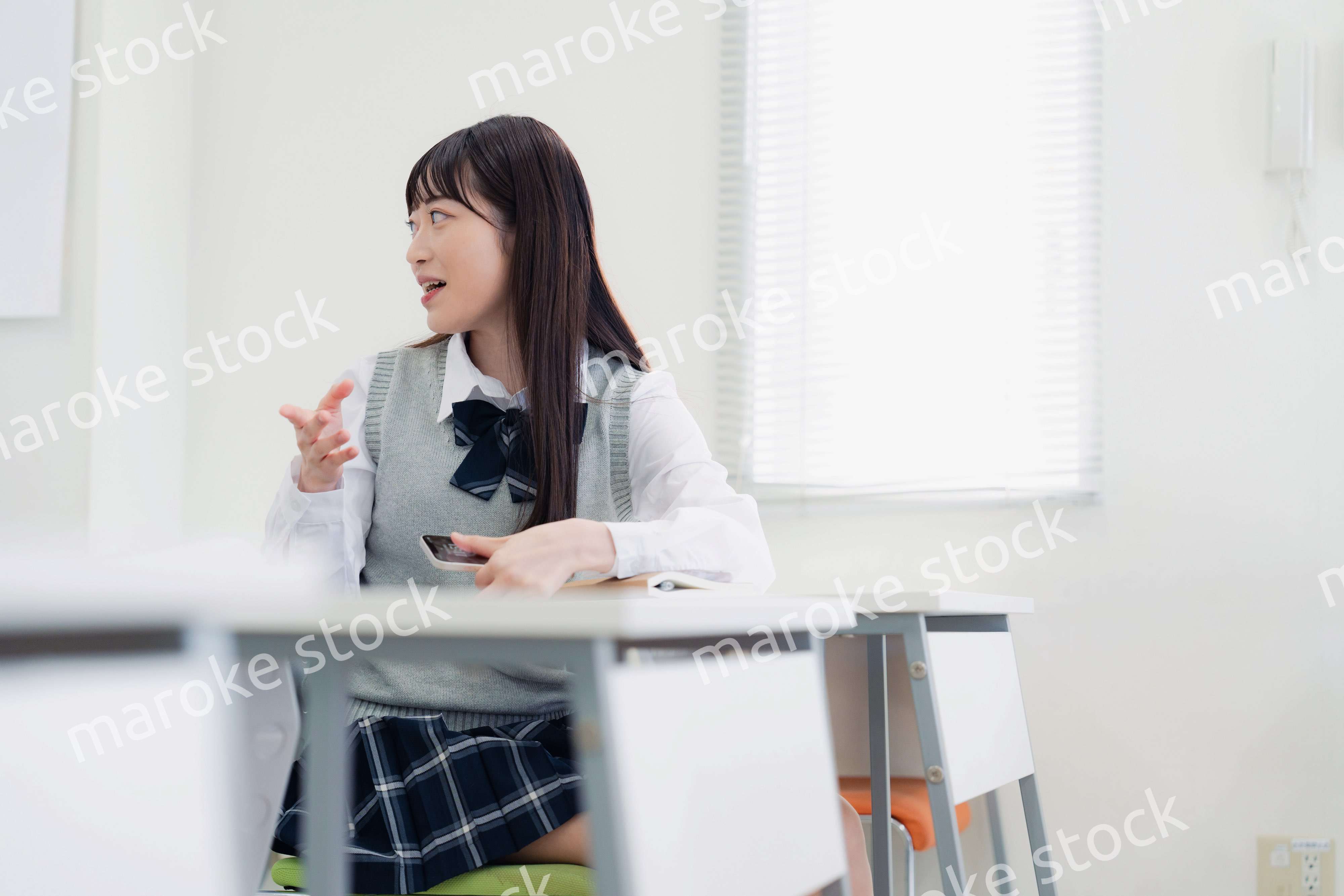 同級生と教室で仲良く話す高校生