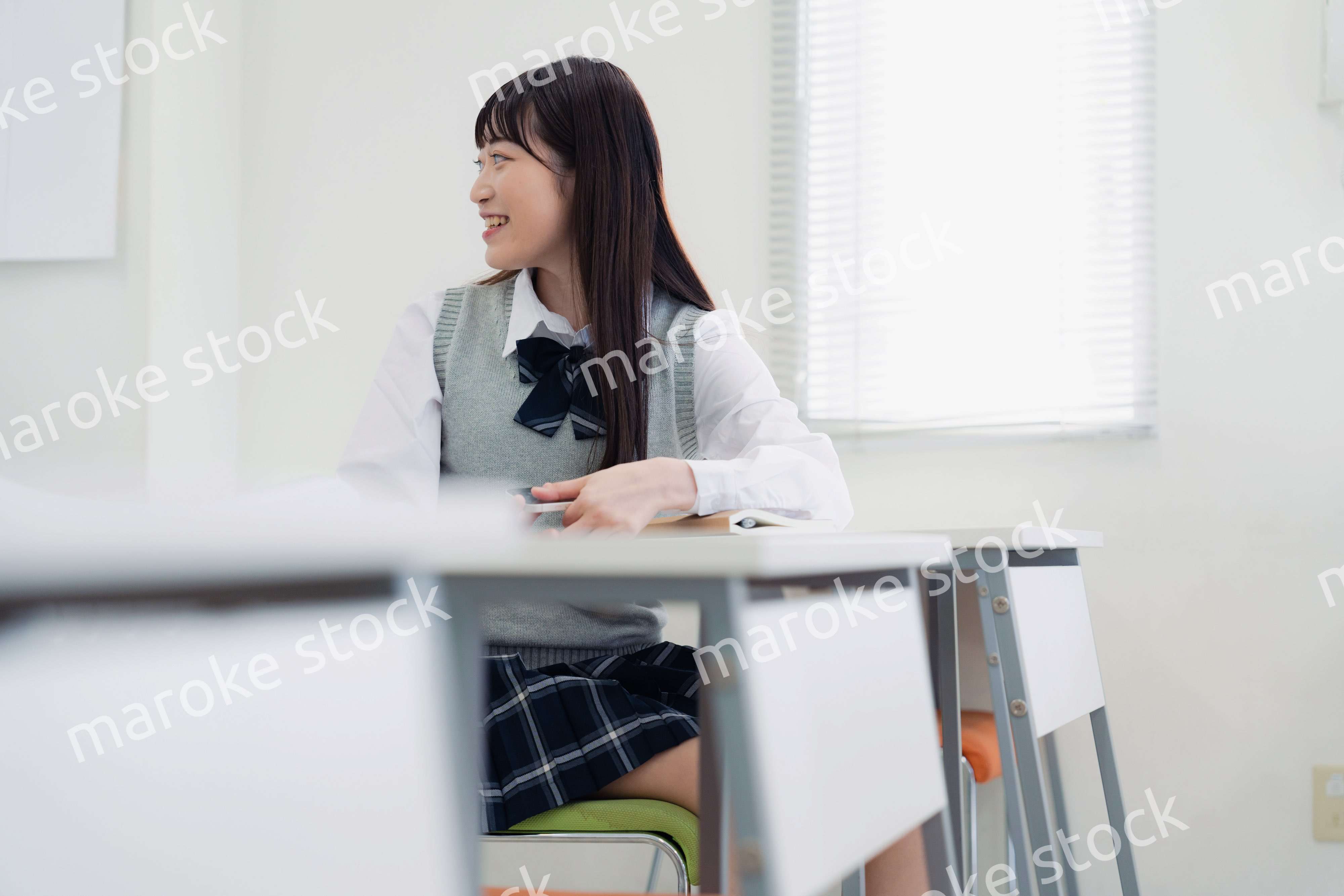 同級生と教室で仲良く話す高校生