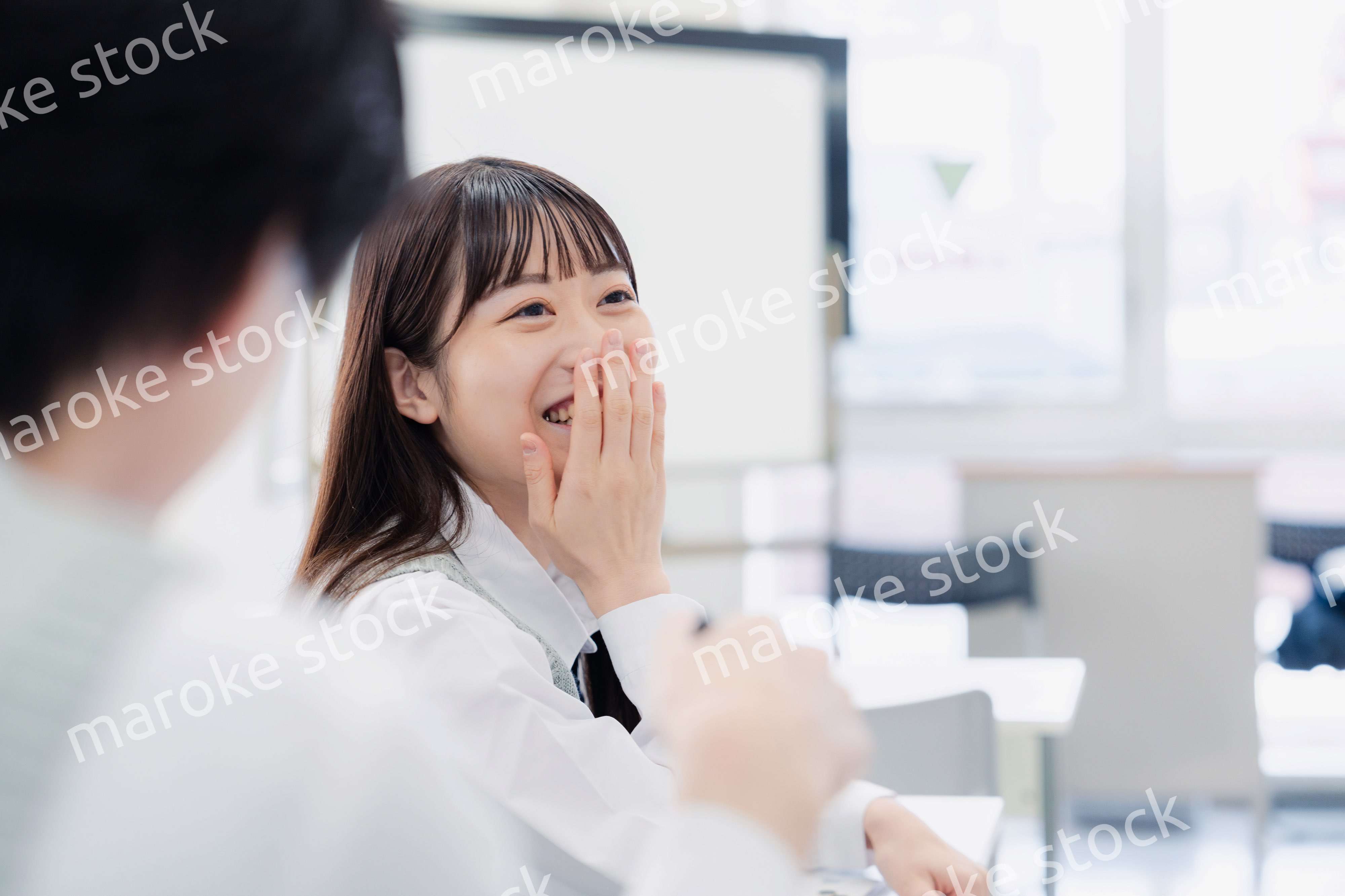 同級生と教室で仲良く話す高校生