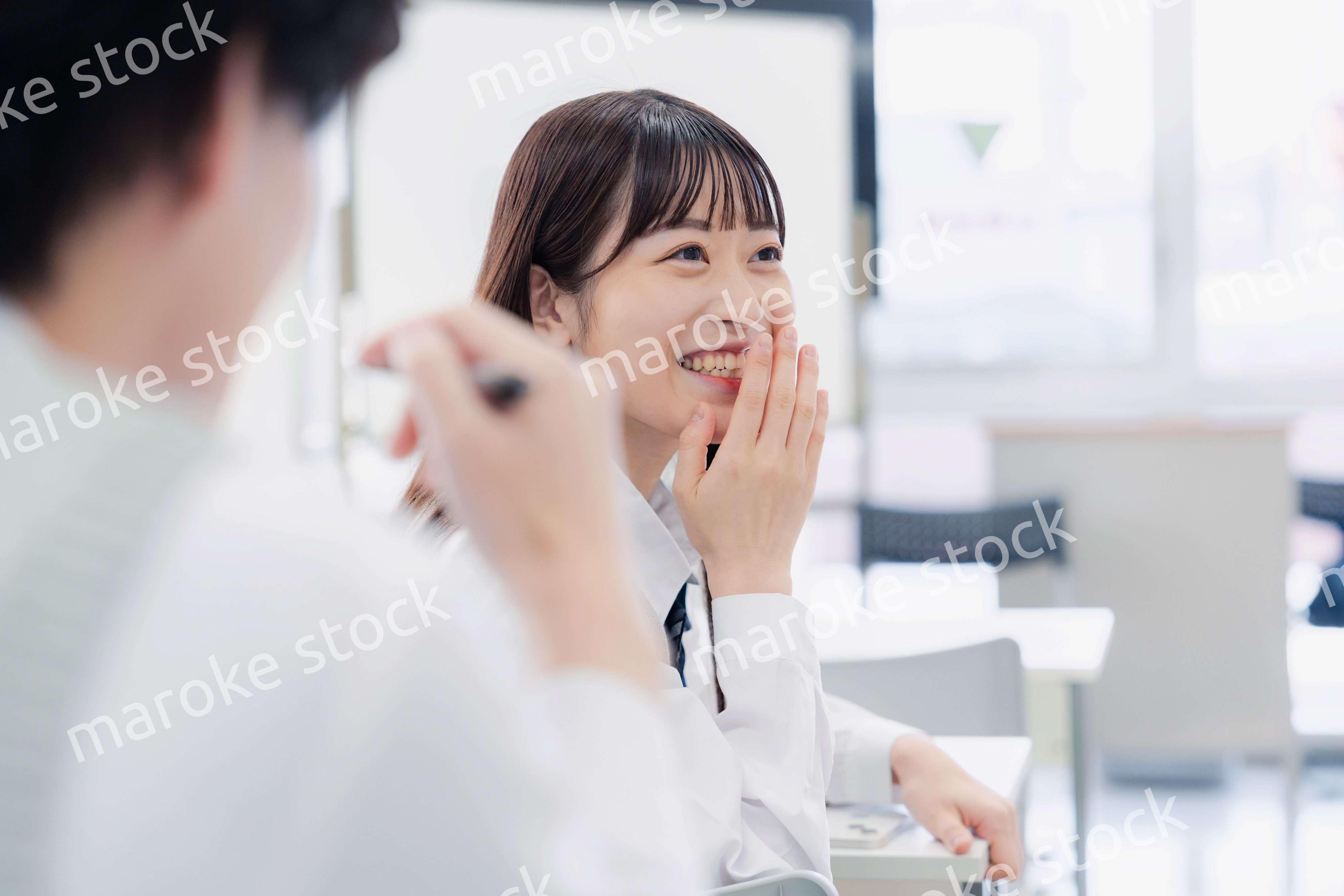 同級生と教室で仲良く話す高校生