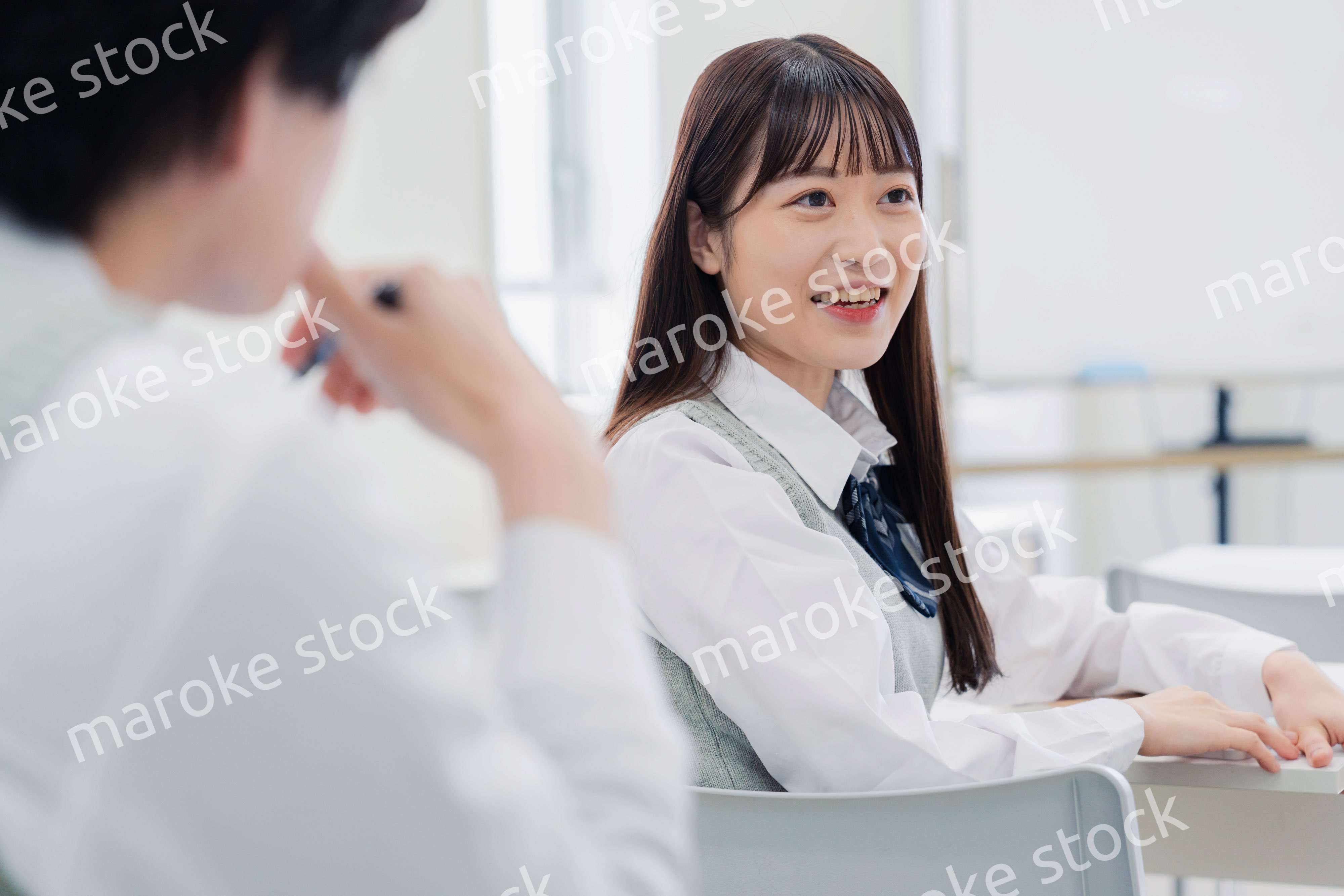 同級生と教室で仲良く話す高校生