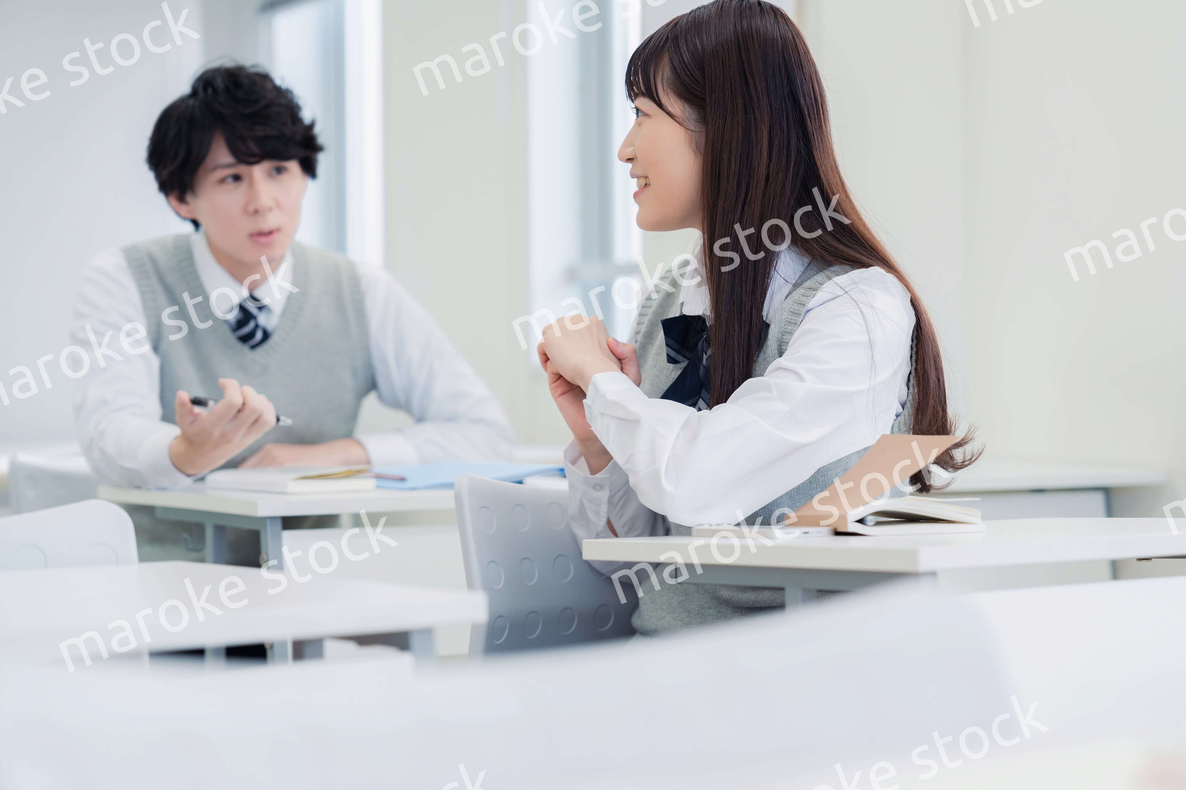 同級生と教室で仲良く話す高校生