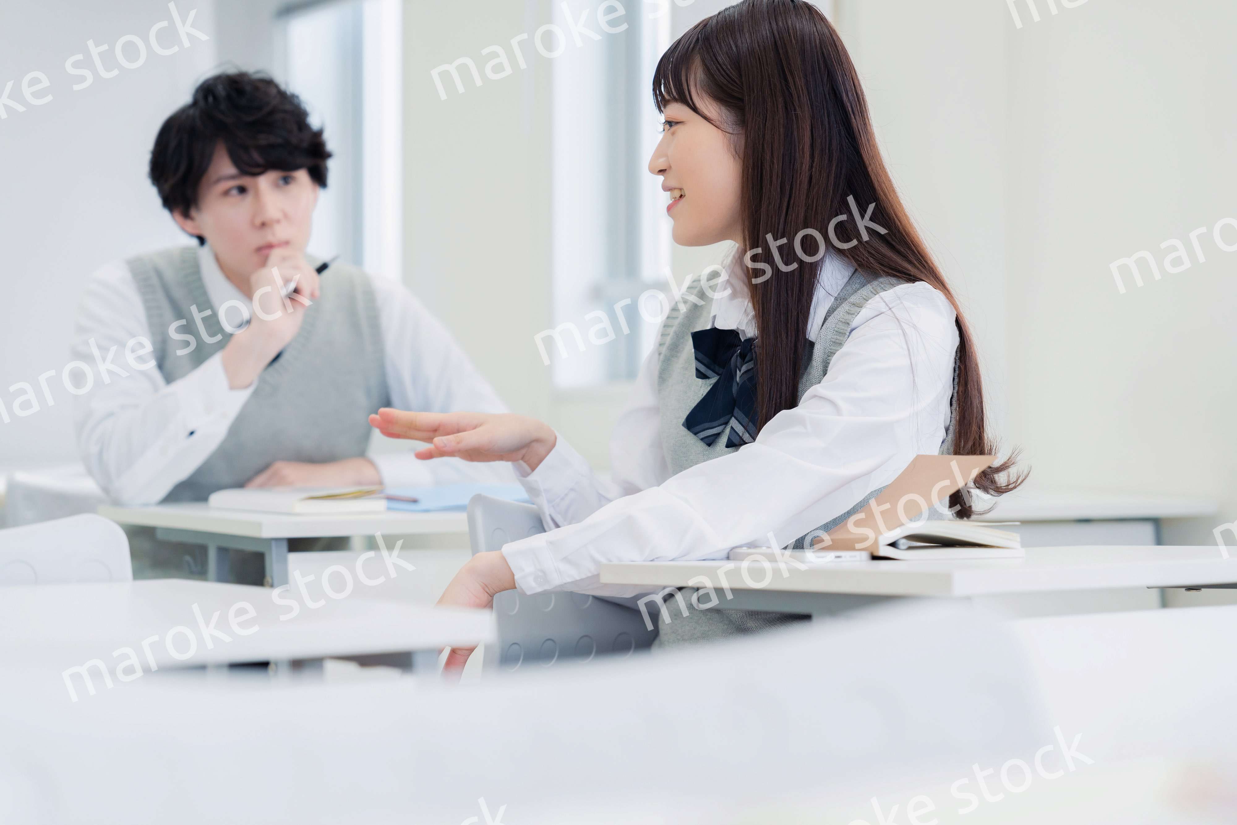 同級生と教室で仲良く話す高校生