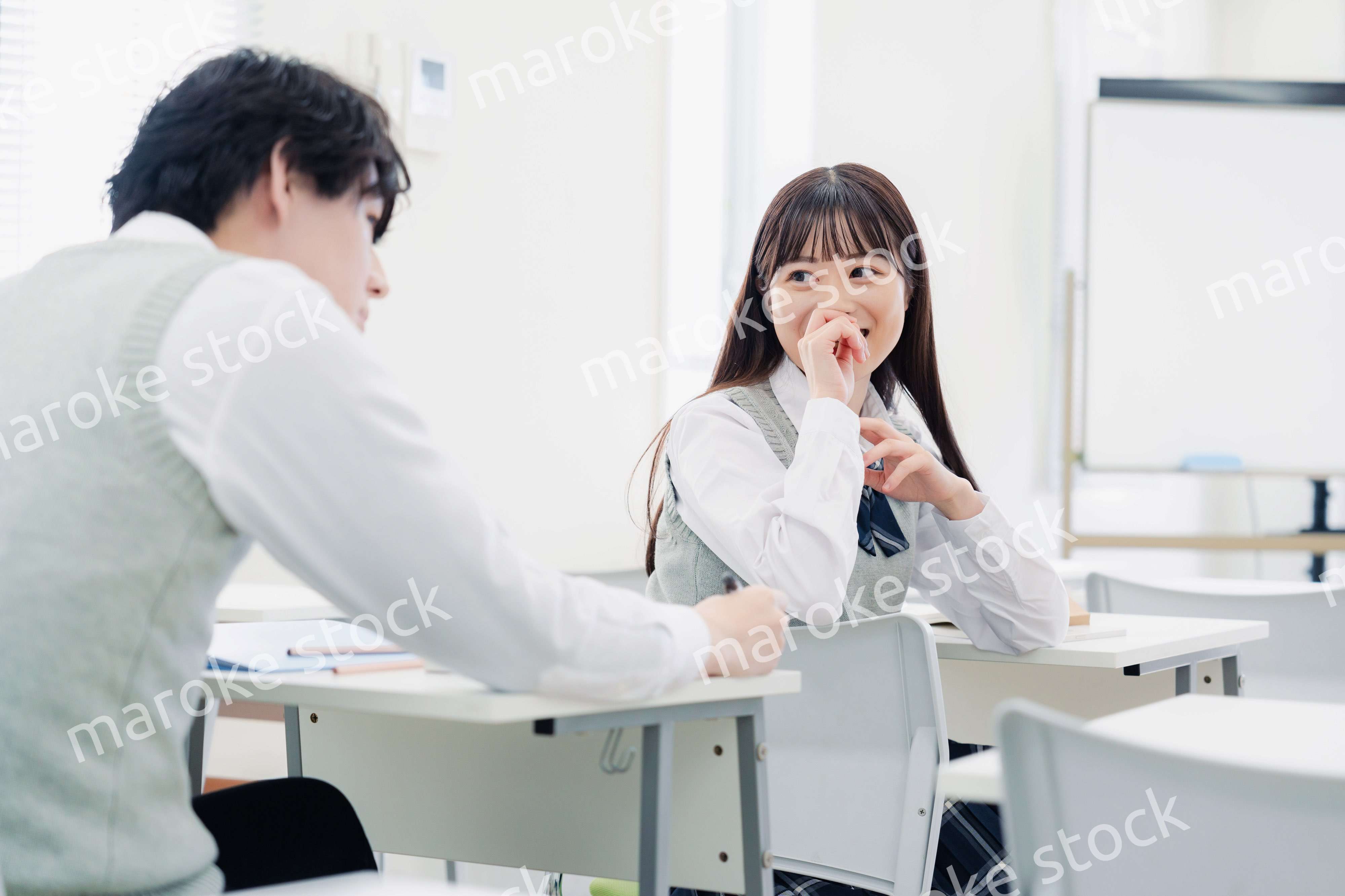 同級生と教室で仲良く話す高校生