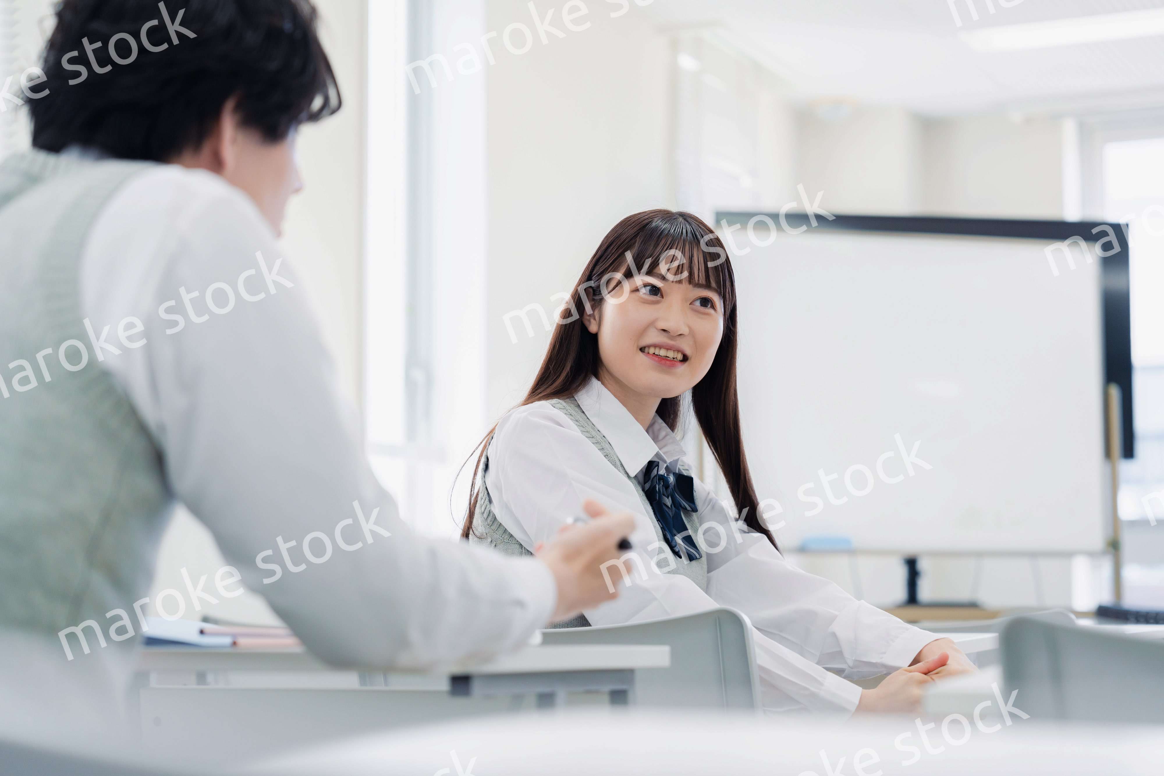 同級生と教室で仲良く話す高校生