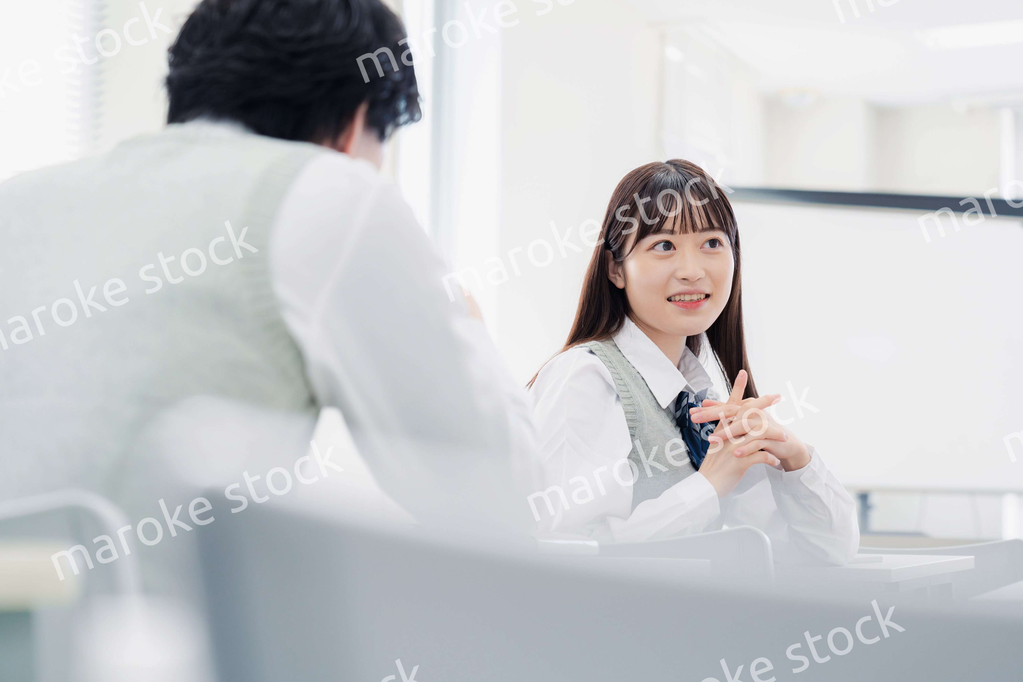 同級生と教室で仲良く話す高校生