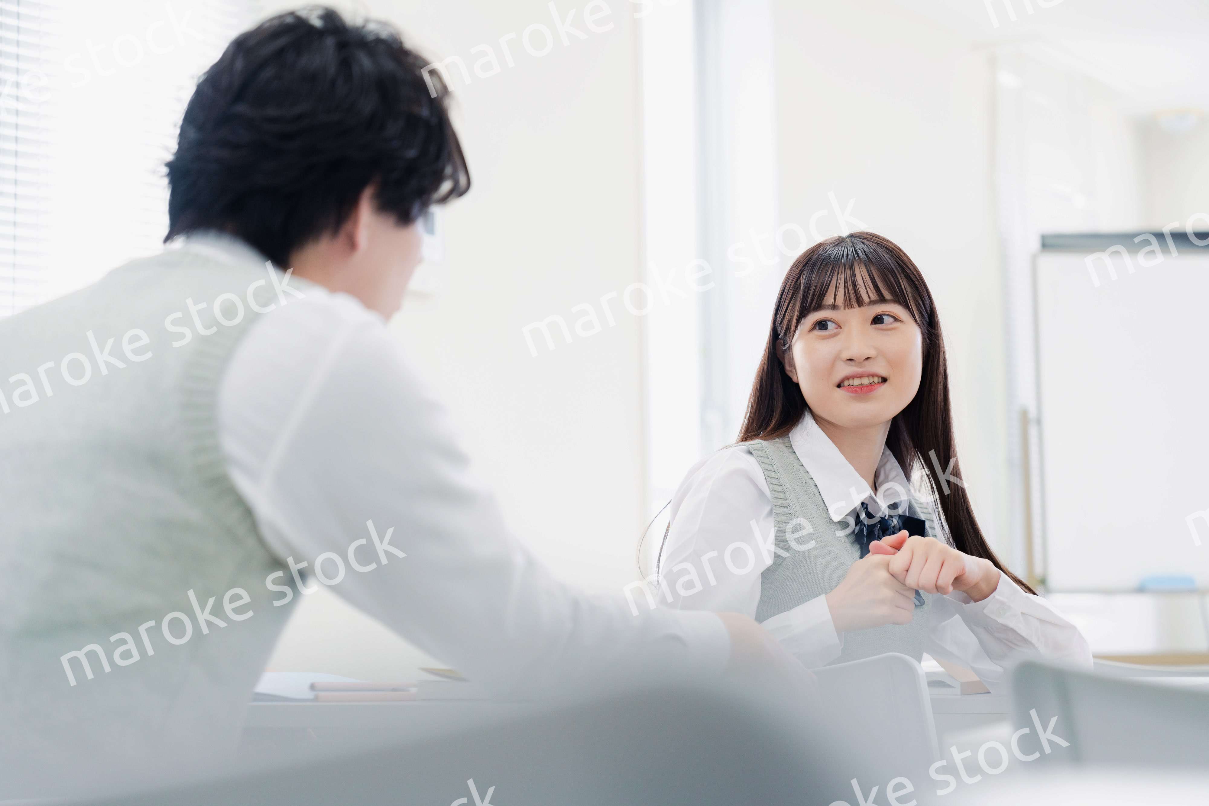 同級生と教室で仲良く話す高校生