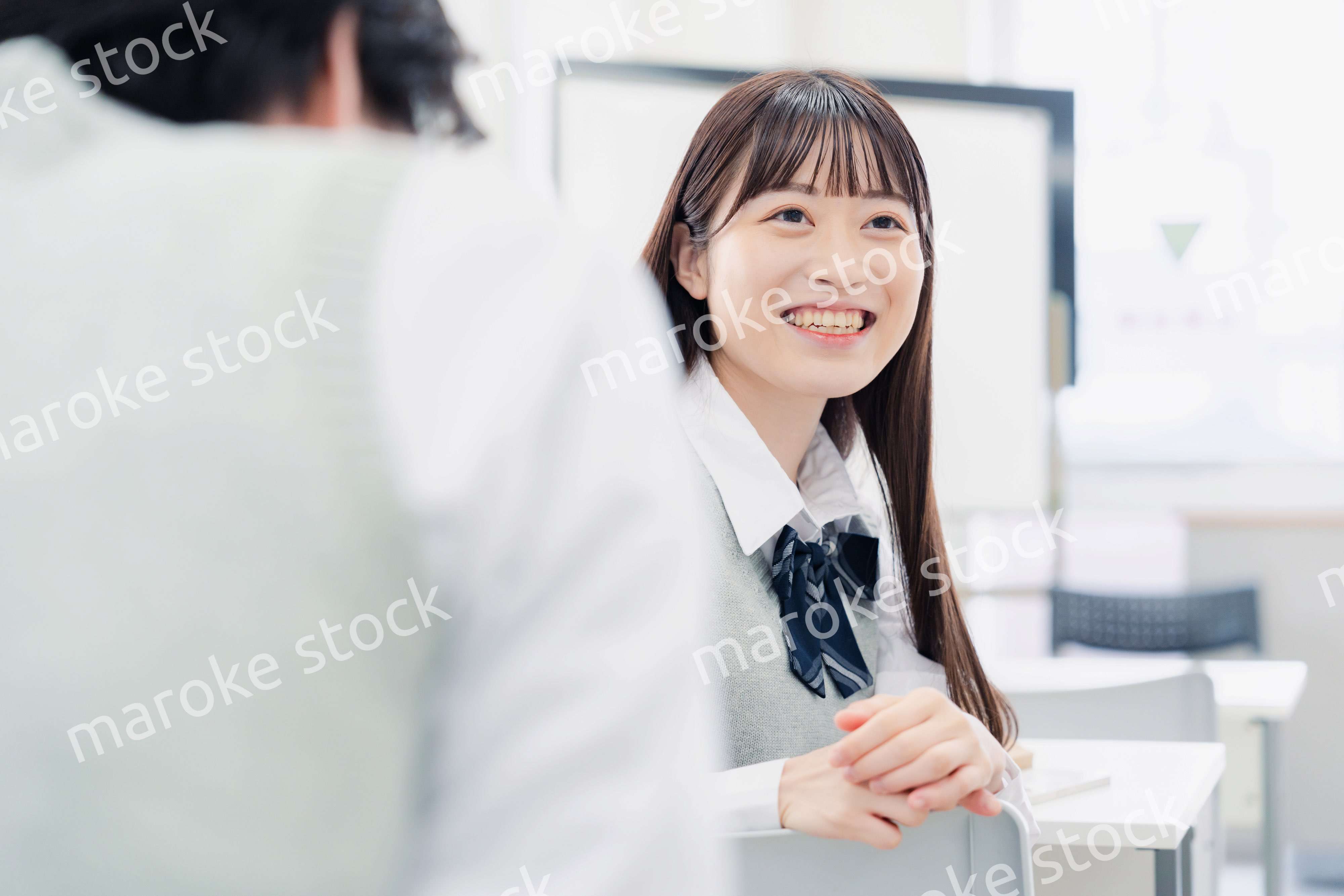 同級生と教室で仲良く話す高校生