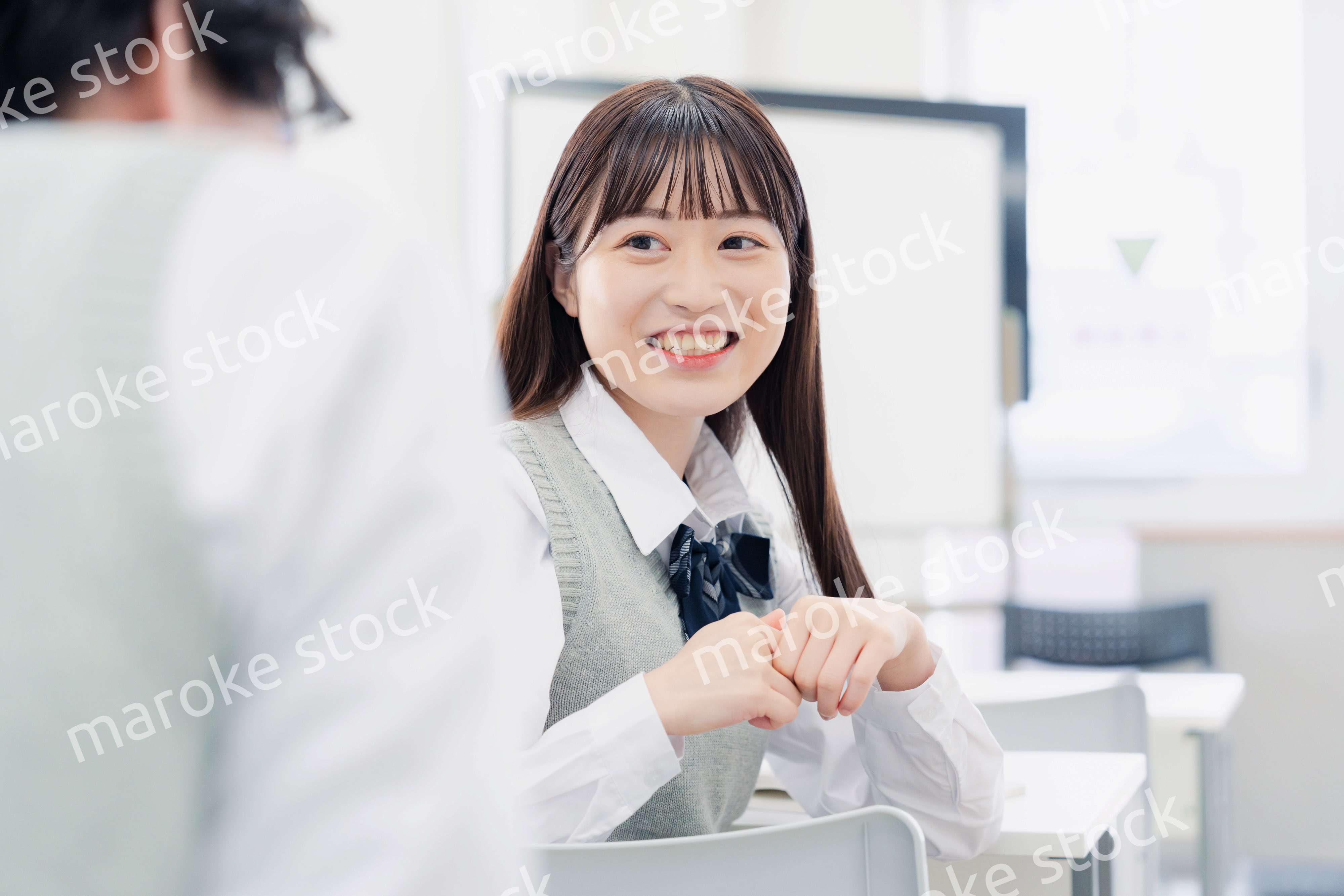 同級生と教室で仲良く話す高校生