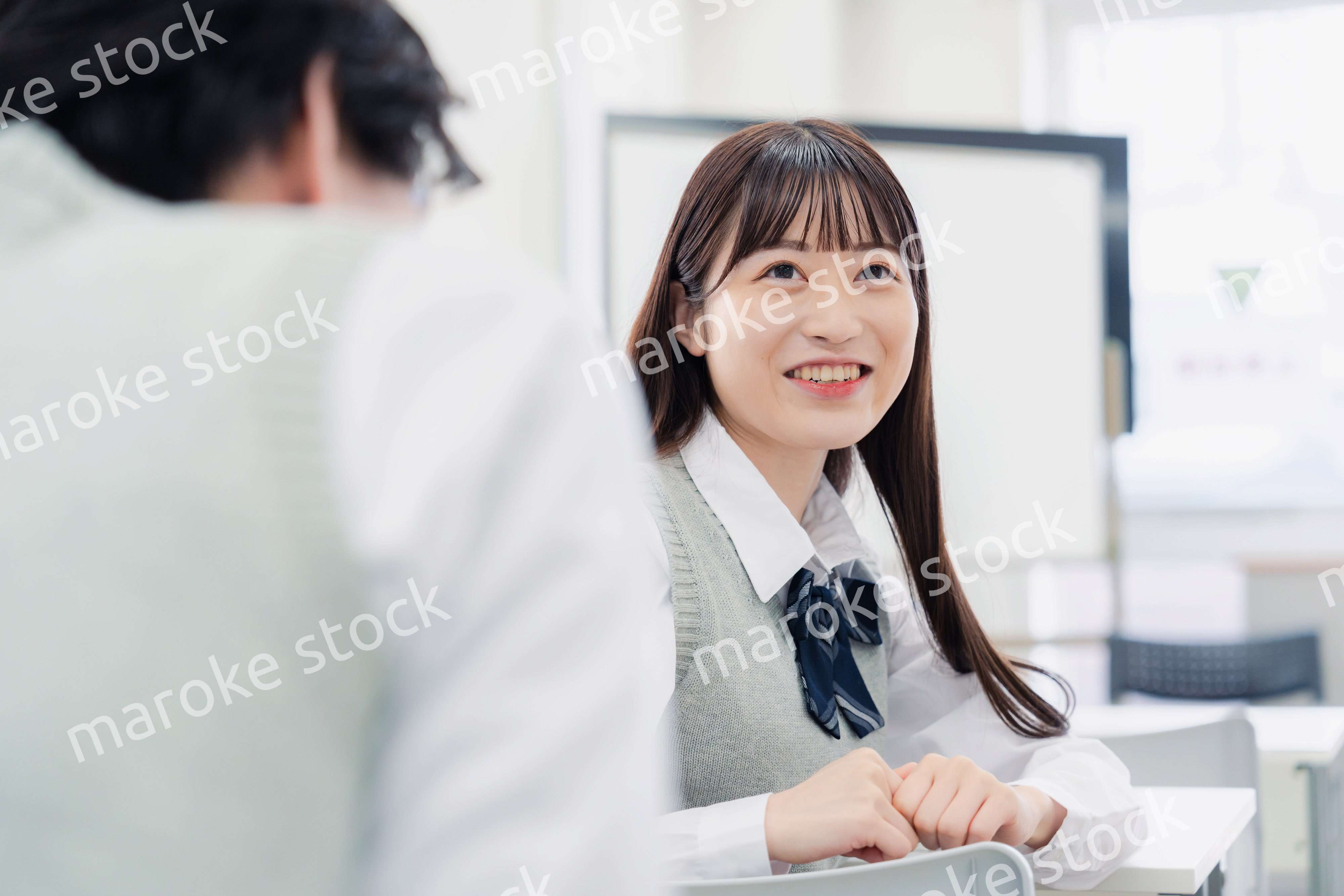 同級生と教室で仲良く話す高校生