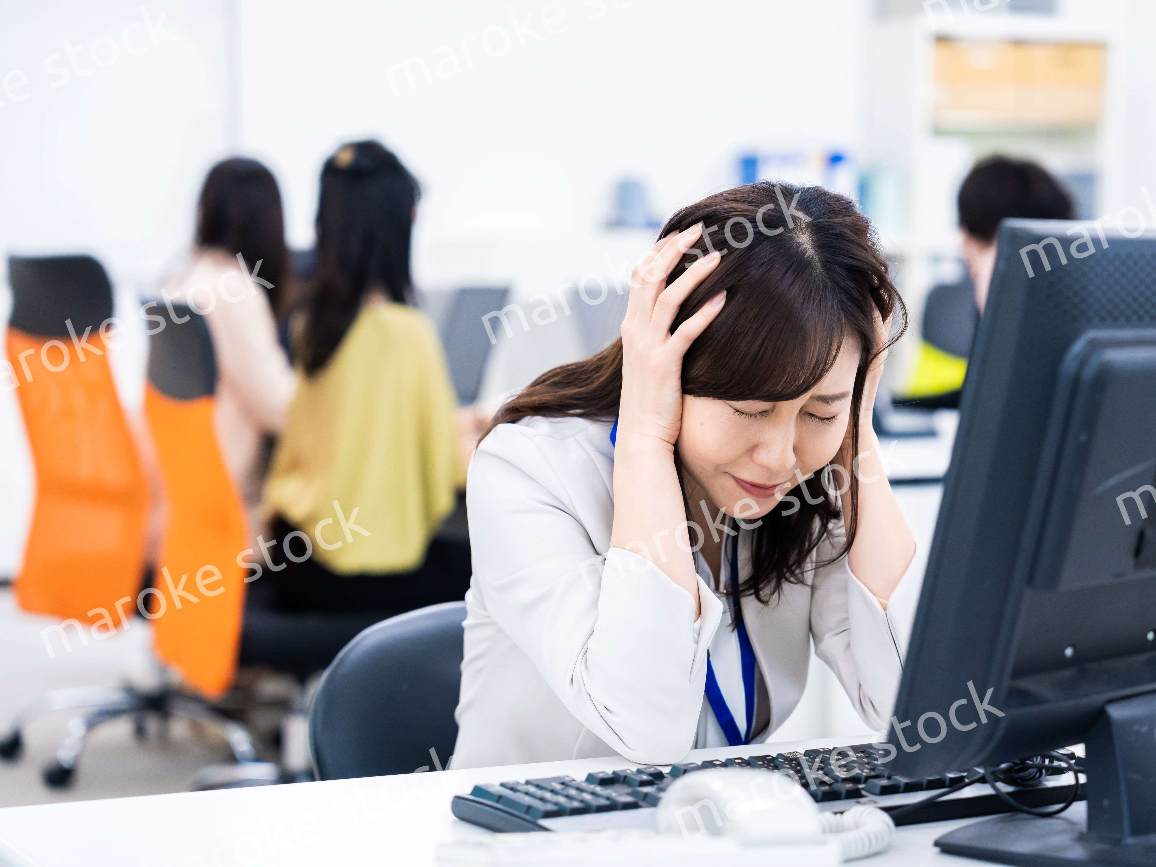 デスクワークをしながら頭を抱えるビジネスウーマン