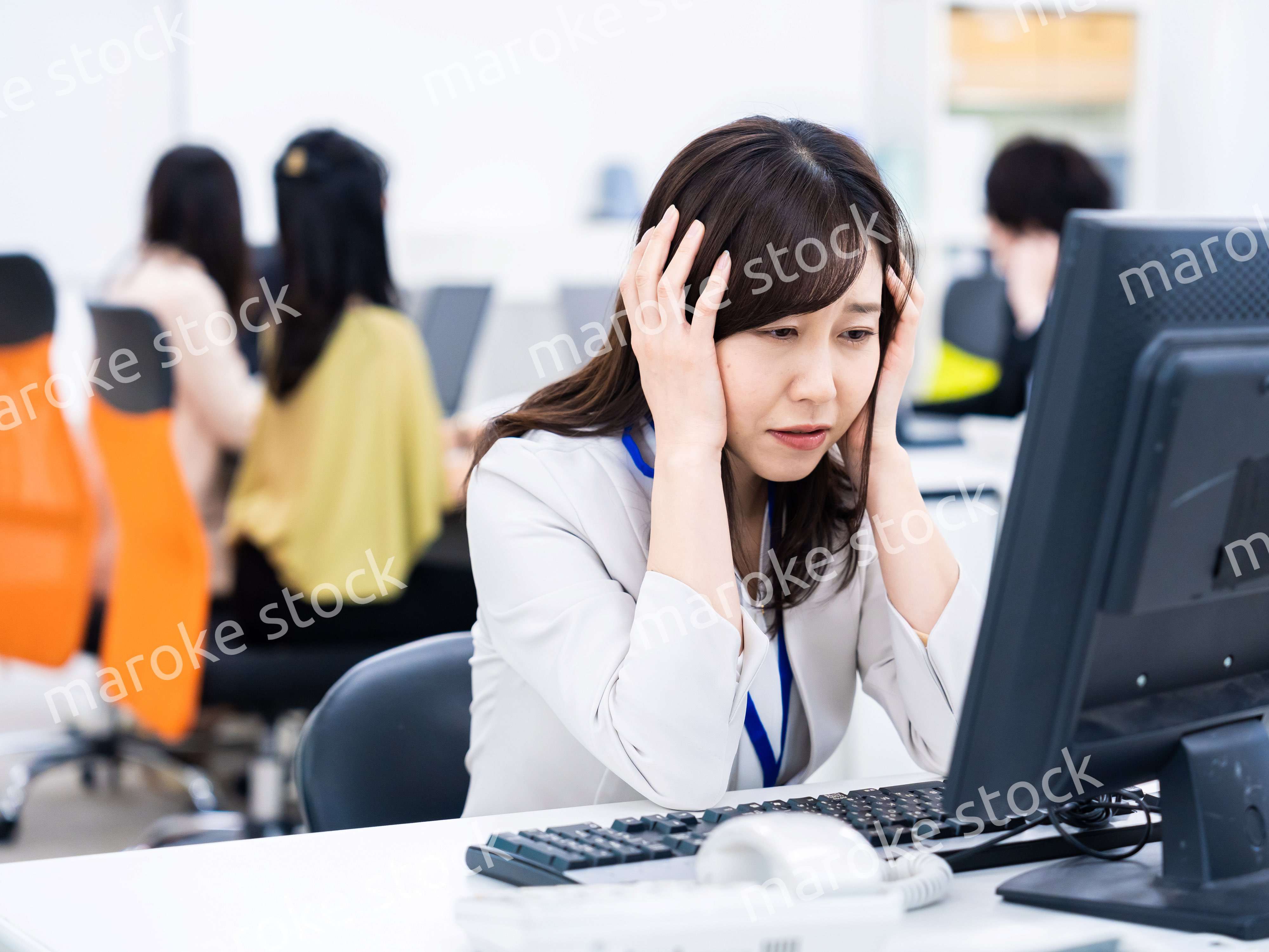デスクワークをしながら頭を抱えるビジネスウーマン