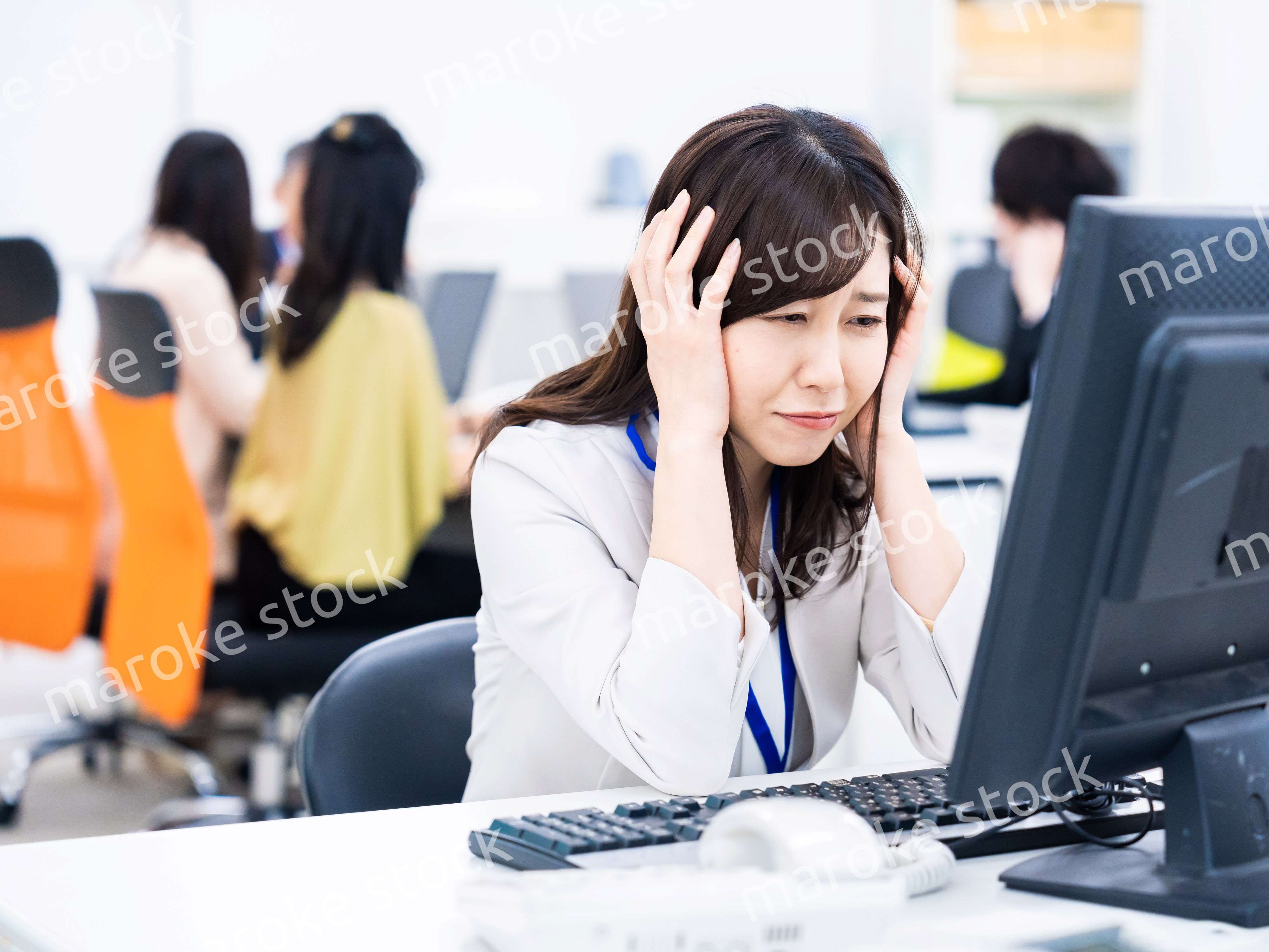 デスクワークをしながら頭を抱えるビジネスウーマン