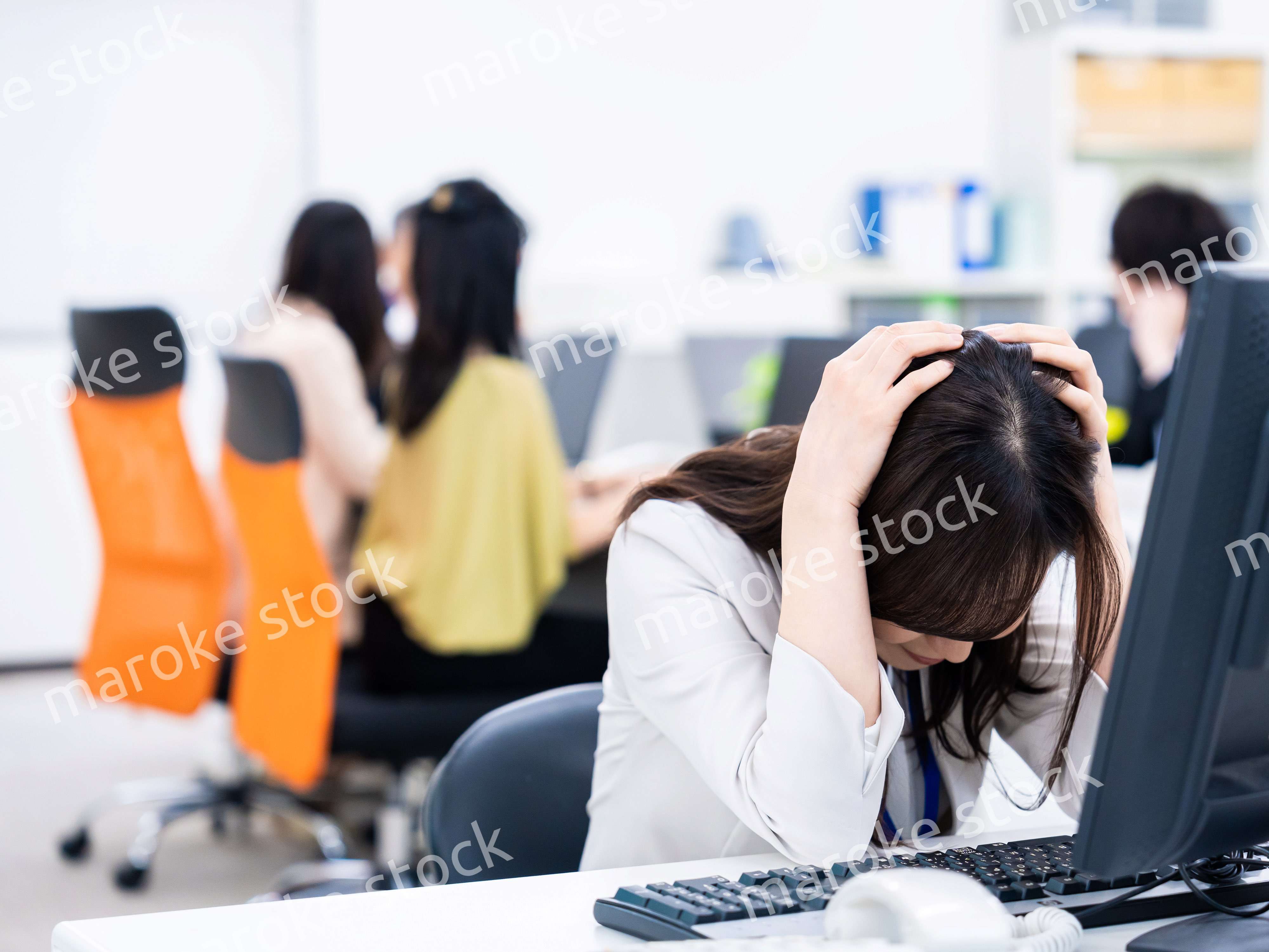 デスクワークをしながら頭を抱えるビジネスウーマン