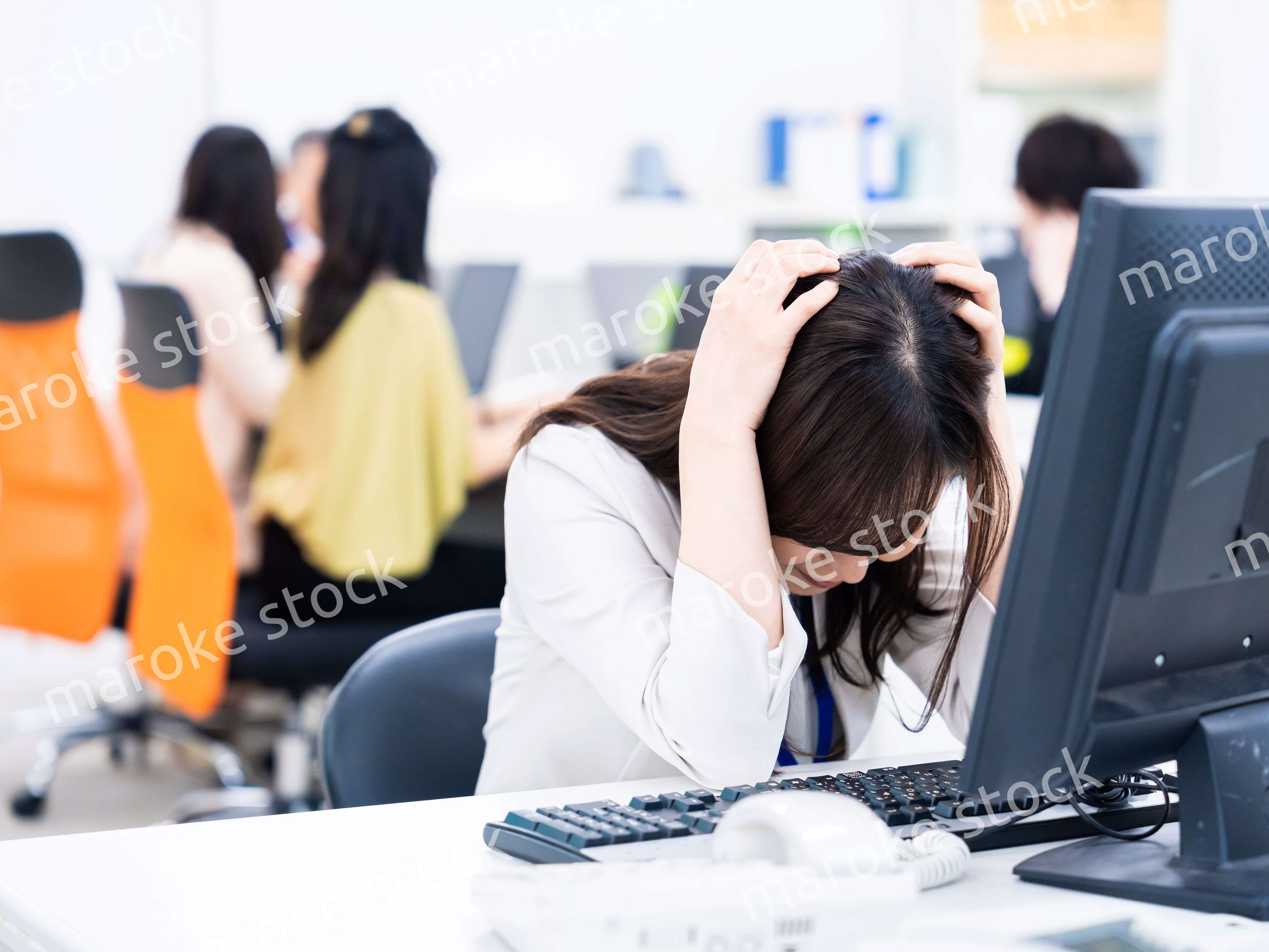デスクワークをしながら頭を抱えるビジネスウーマン
