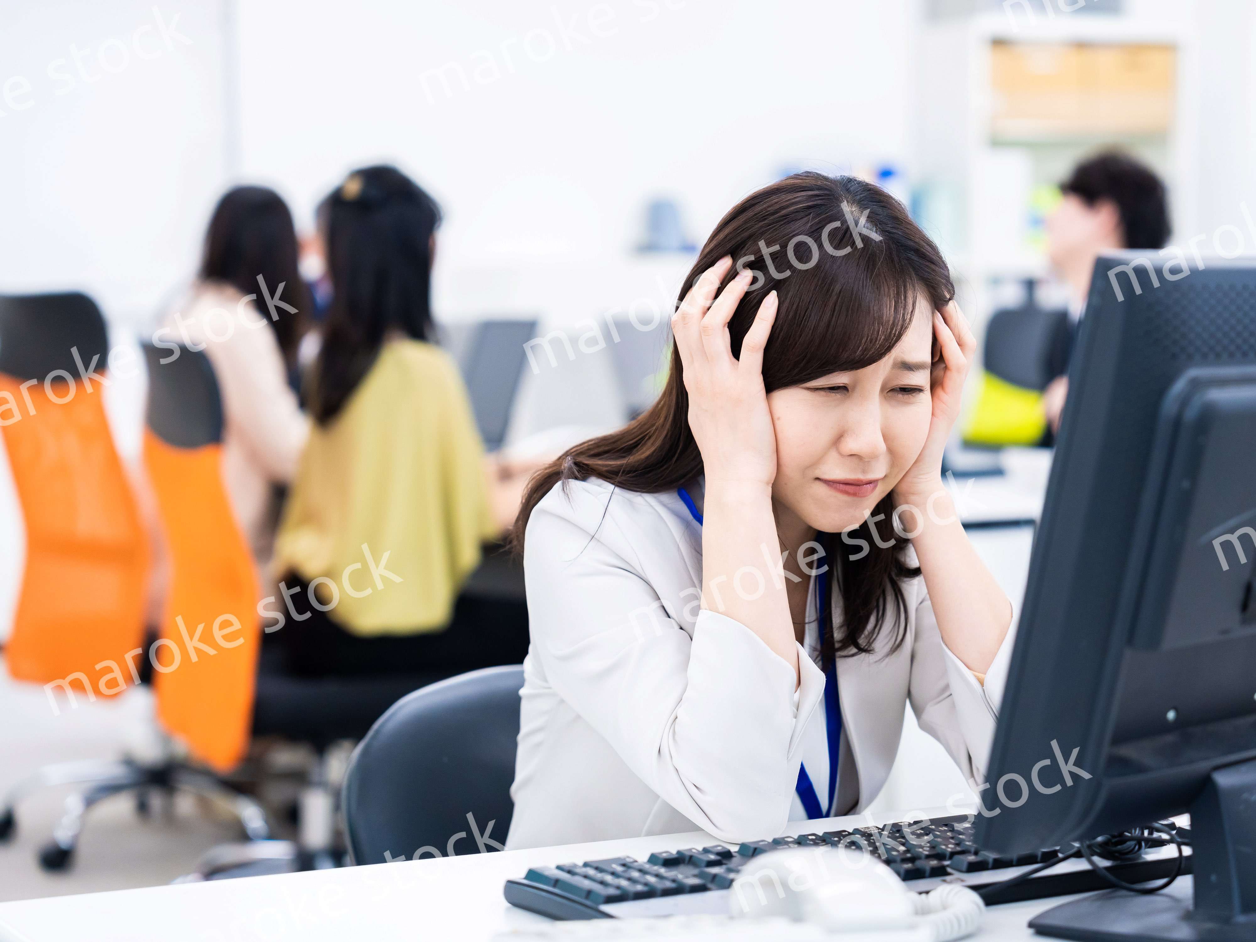 デスクワークをしながら頭を抱えるビジネスウーマン