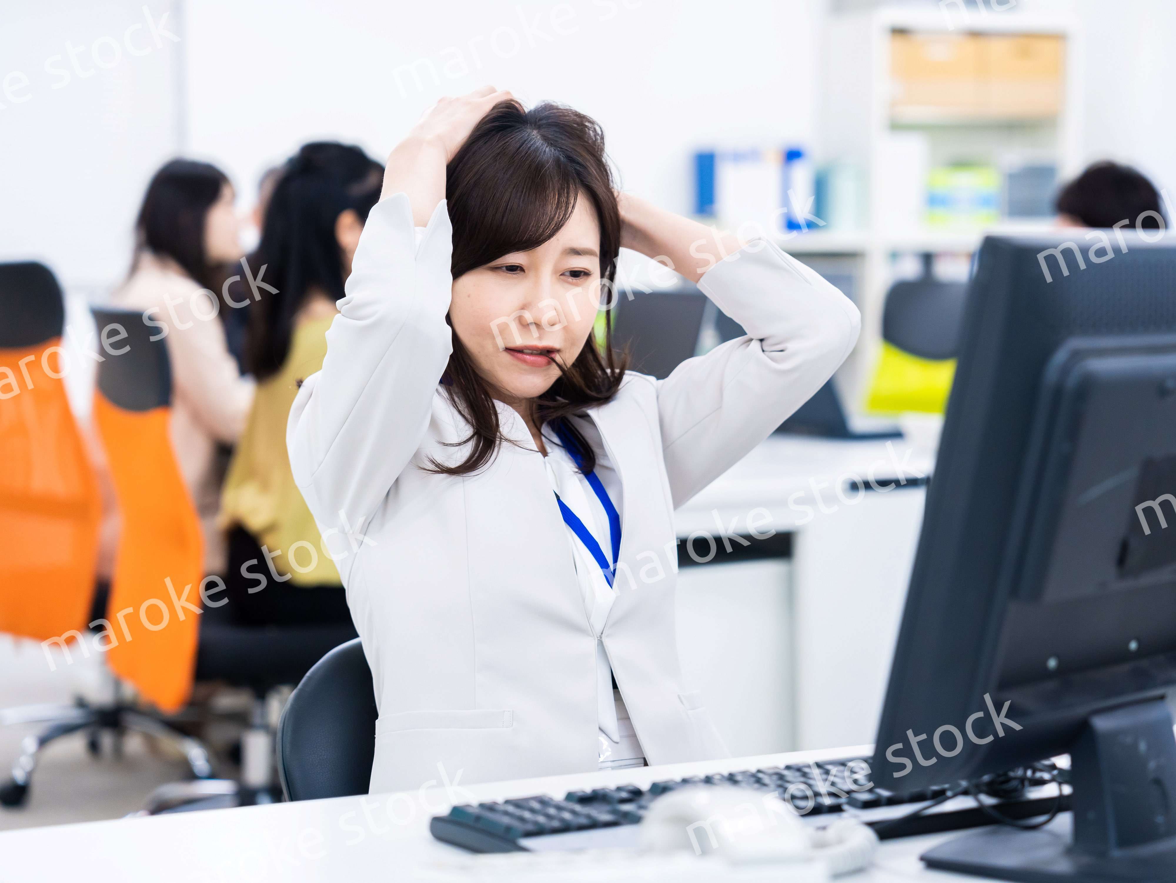 デスクワークをしながら頭を抱えるビジネスウーマン
