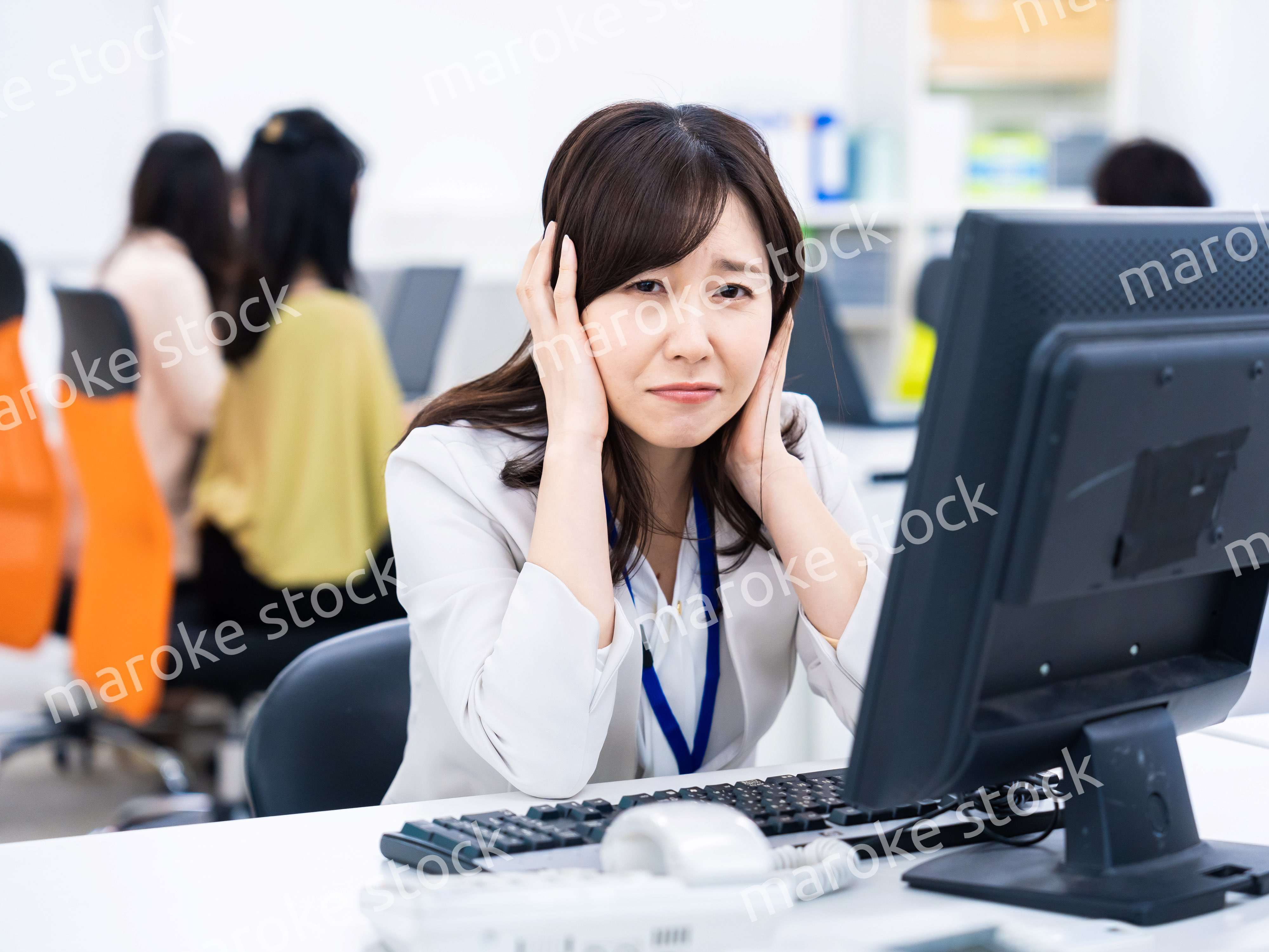 デスクワークをしながら頭を抱えるビジネスウーマン