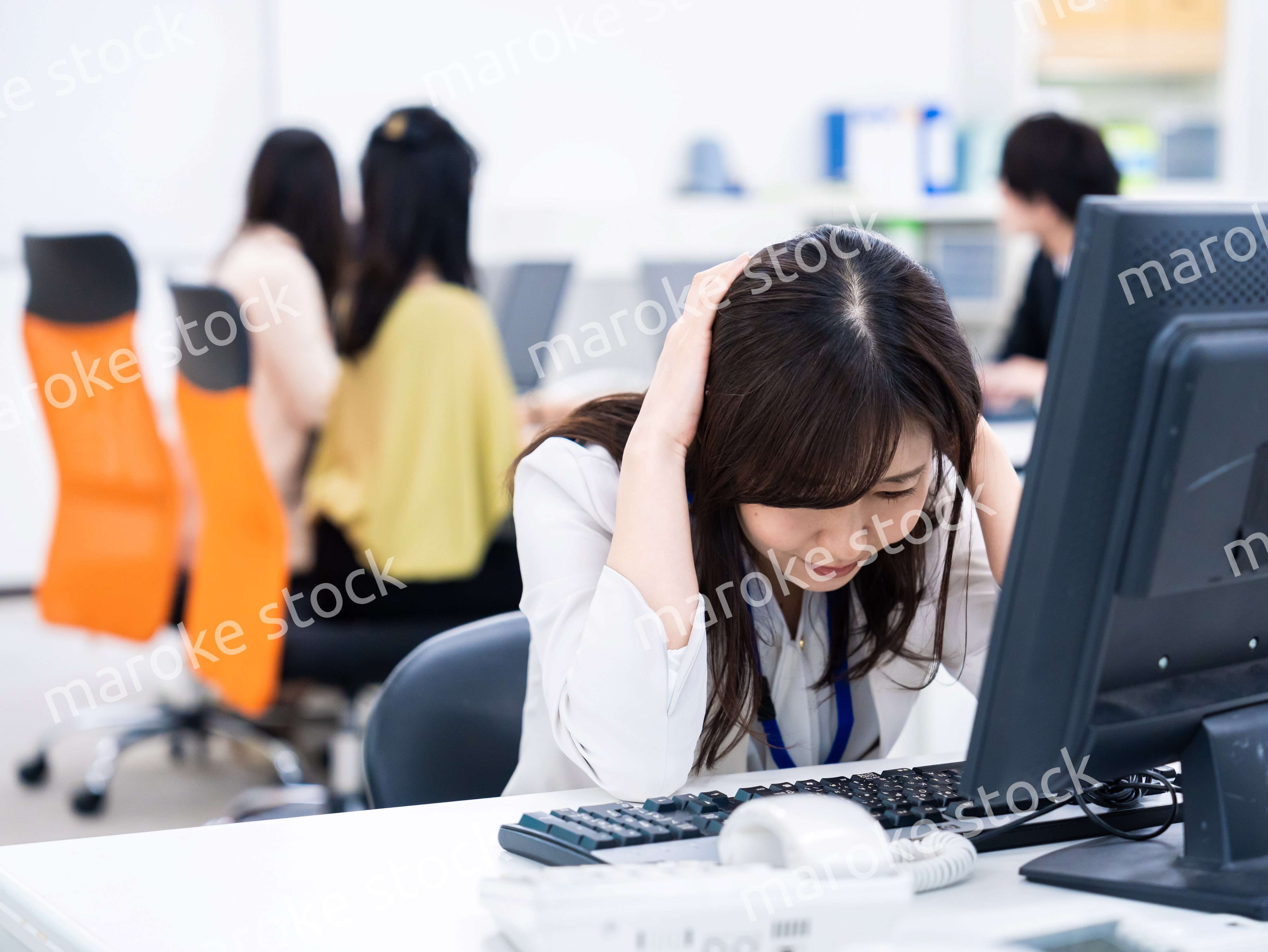 デスクワークをしながら頭を抱えるビジネスウーマン