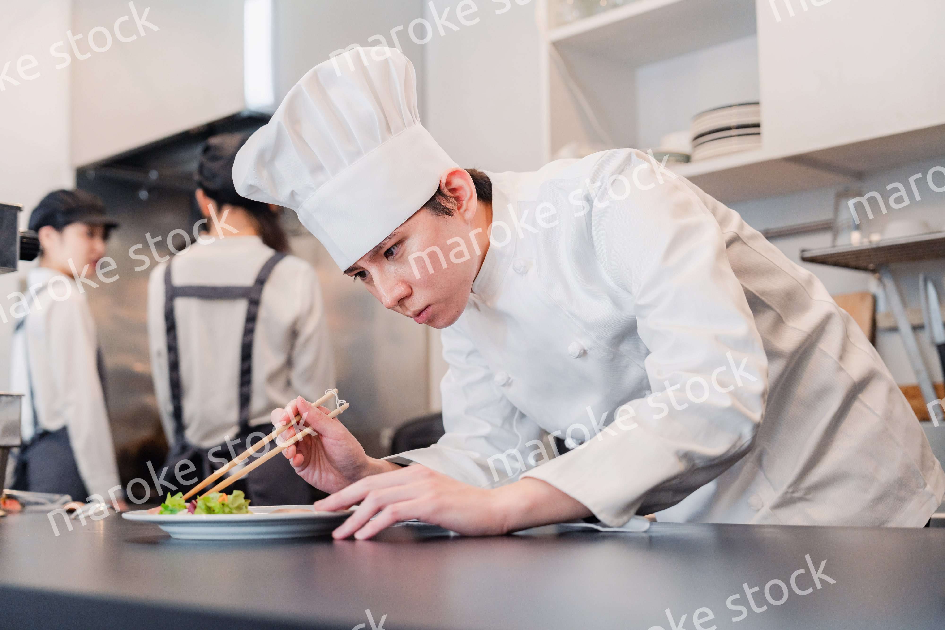 厨房で盛り付けをする男性シェフ