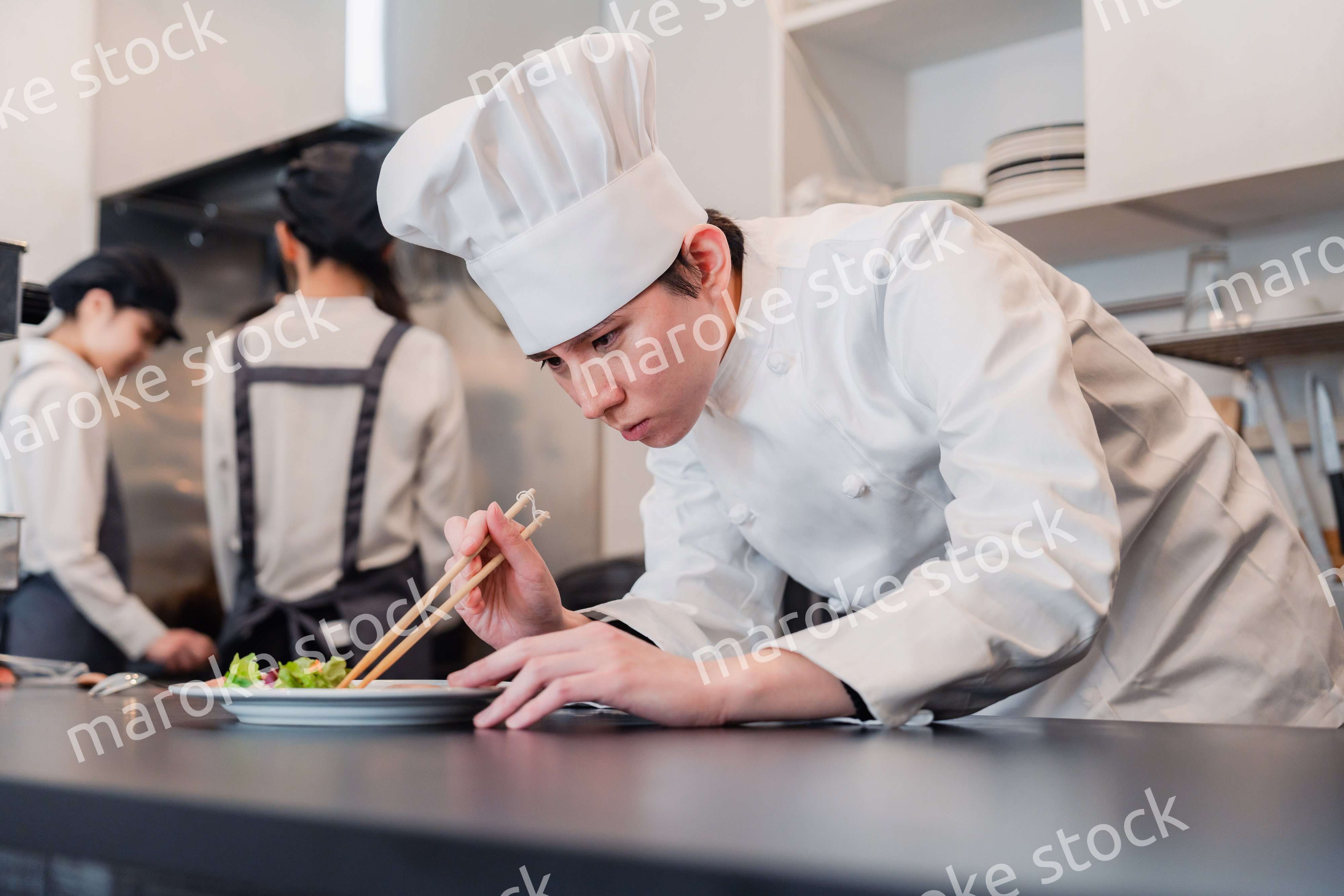 厨房で盛り付けをする男性シェフ