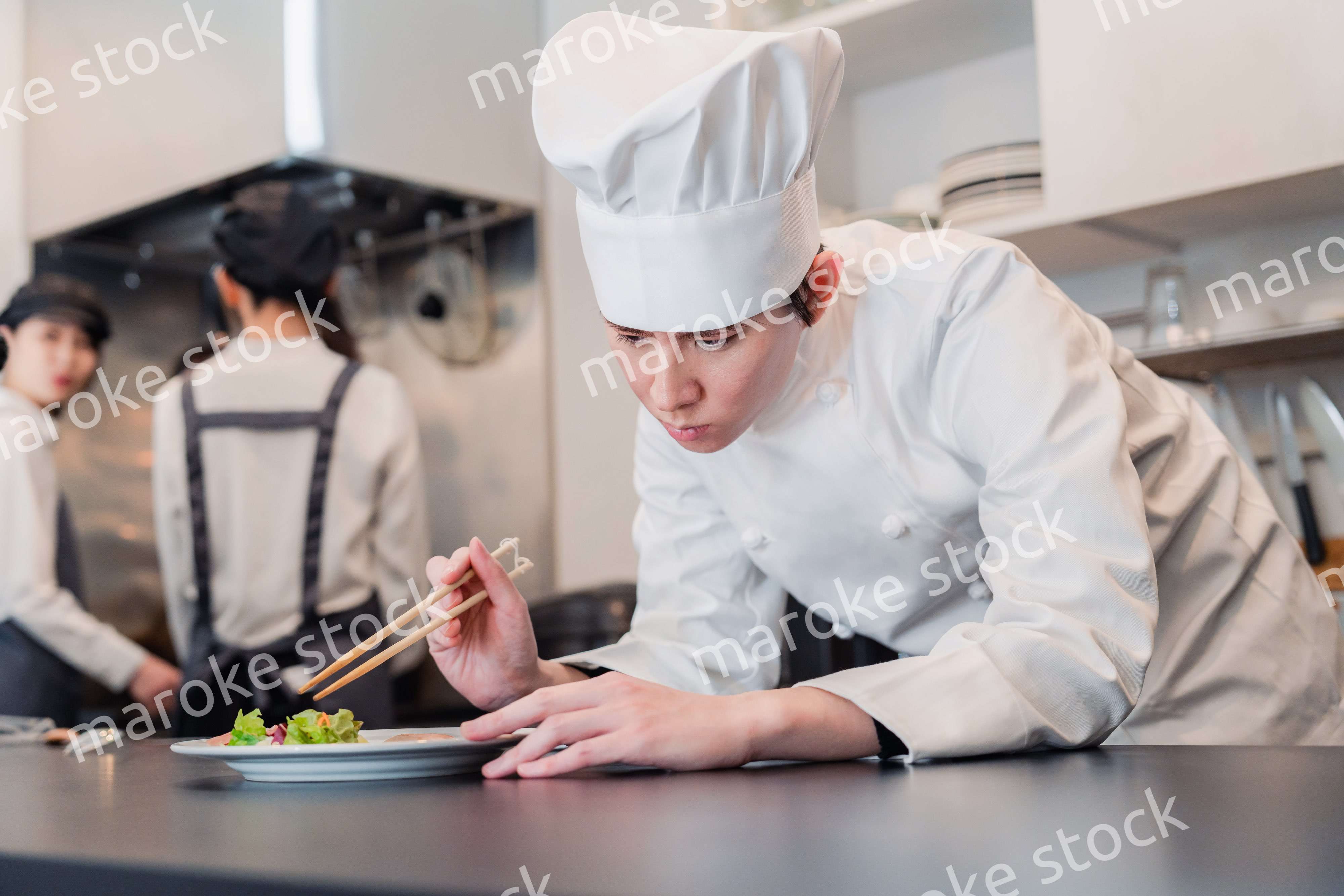 厨房で盛り付けをする男性シェフ