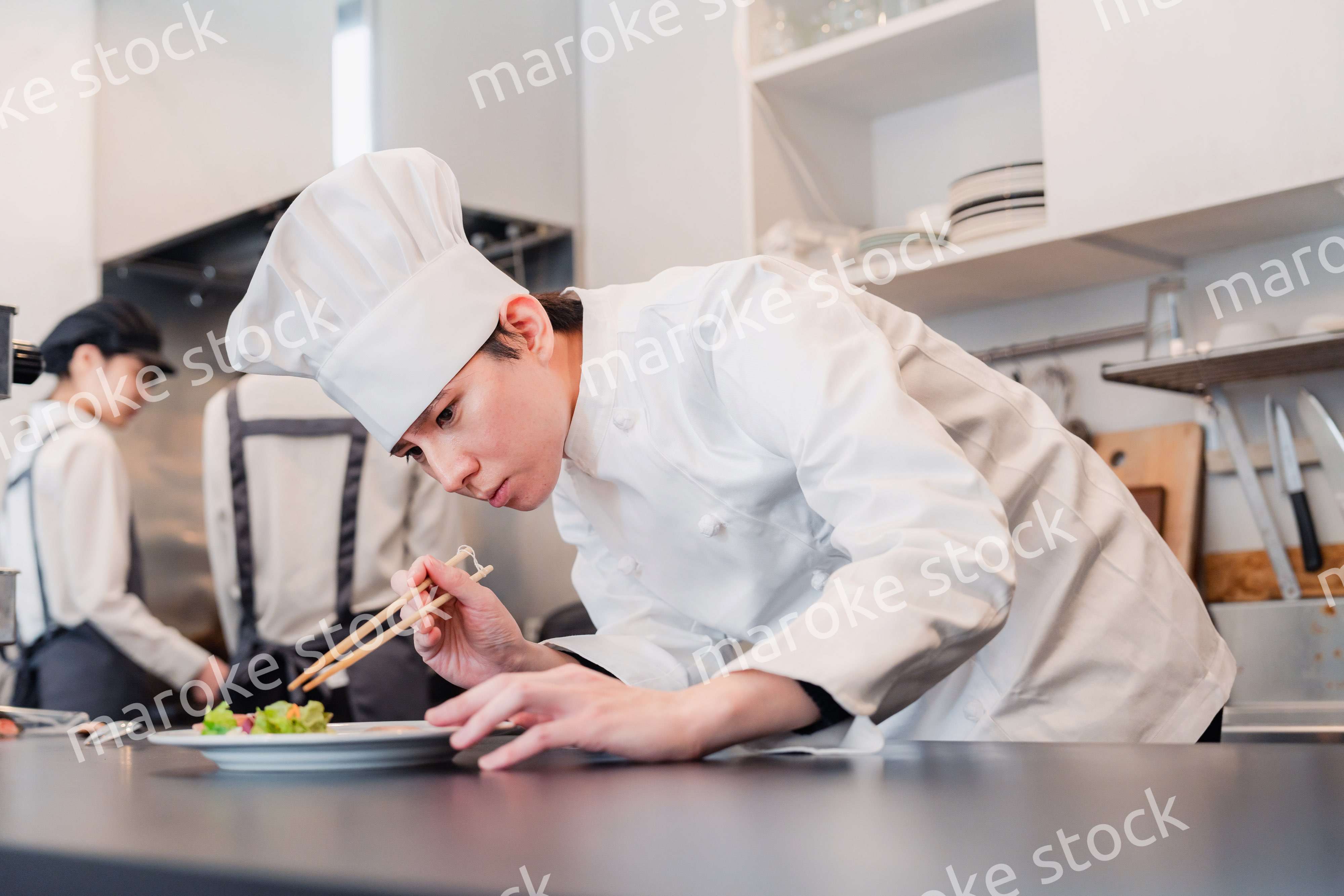 厨房で盛り付けをする男性シェフ