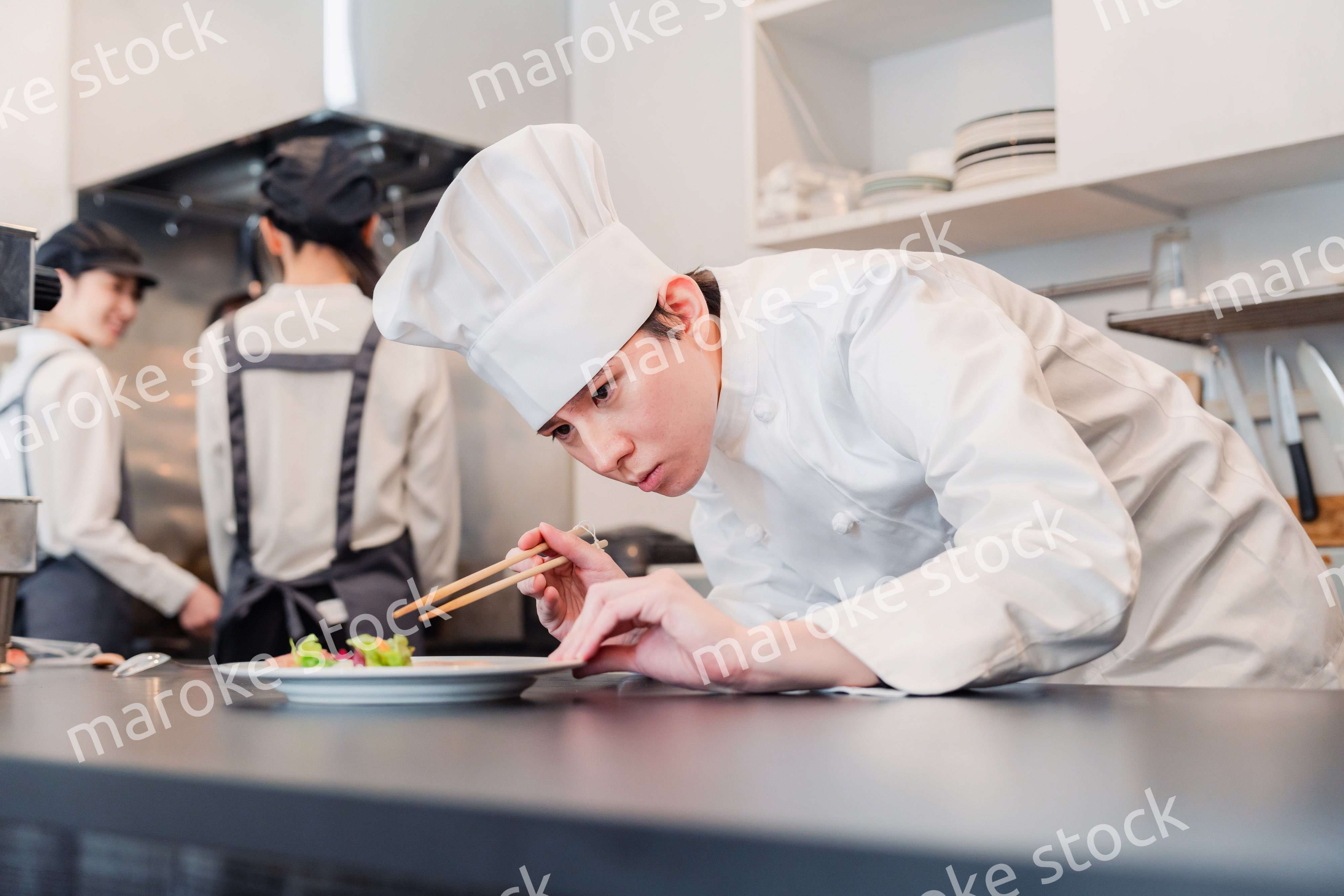 厨房で盛り付けをする男性シェフ