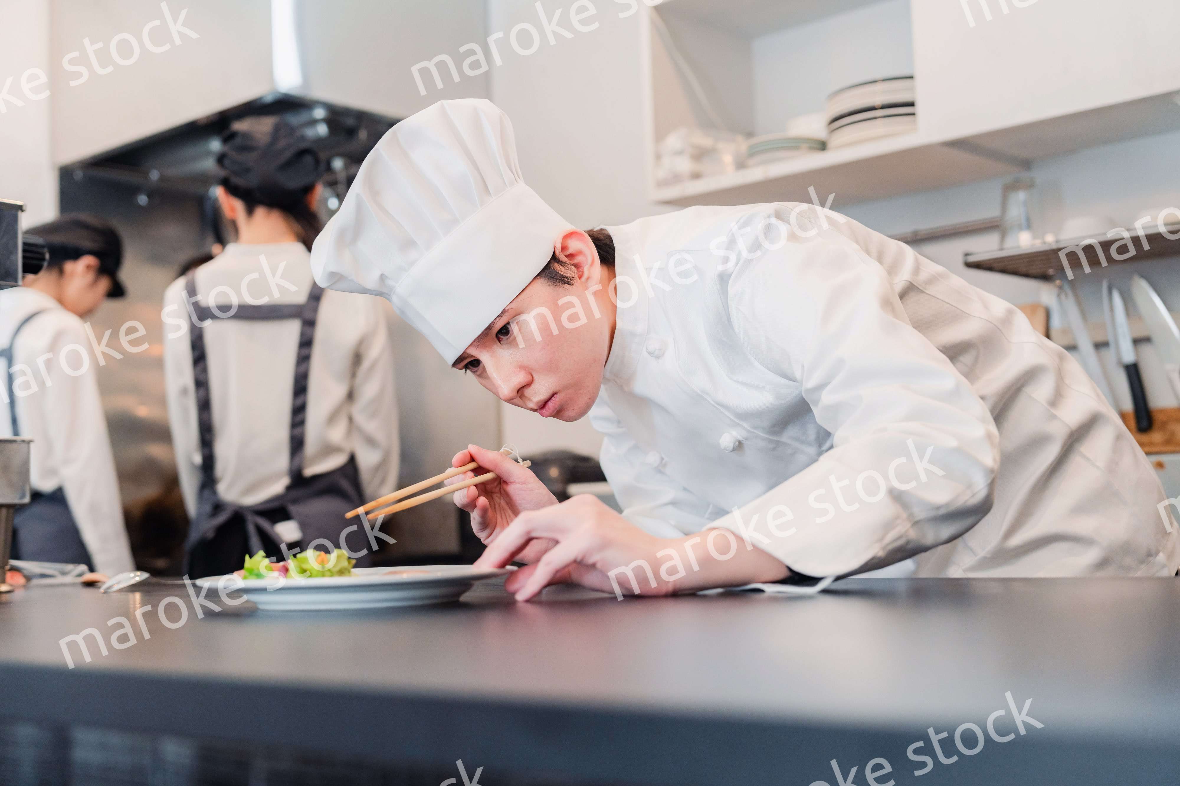 厨房で盛り付けをする男性シェフ