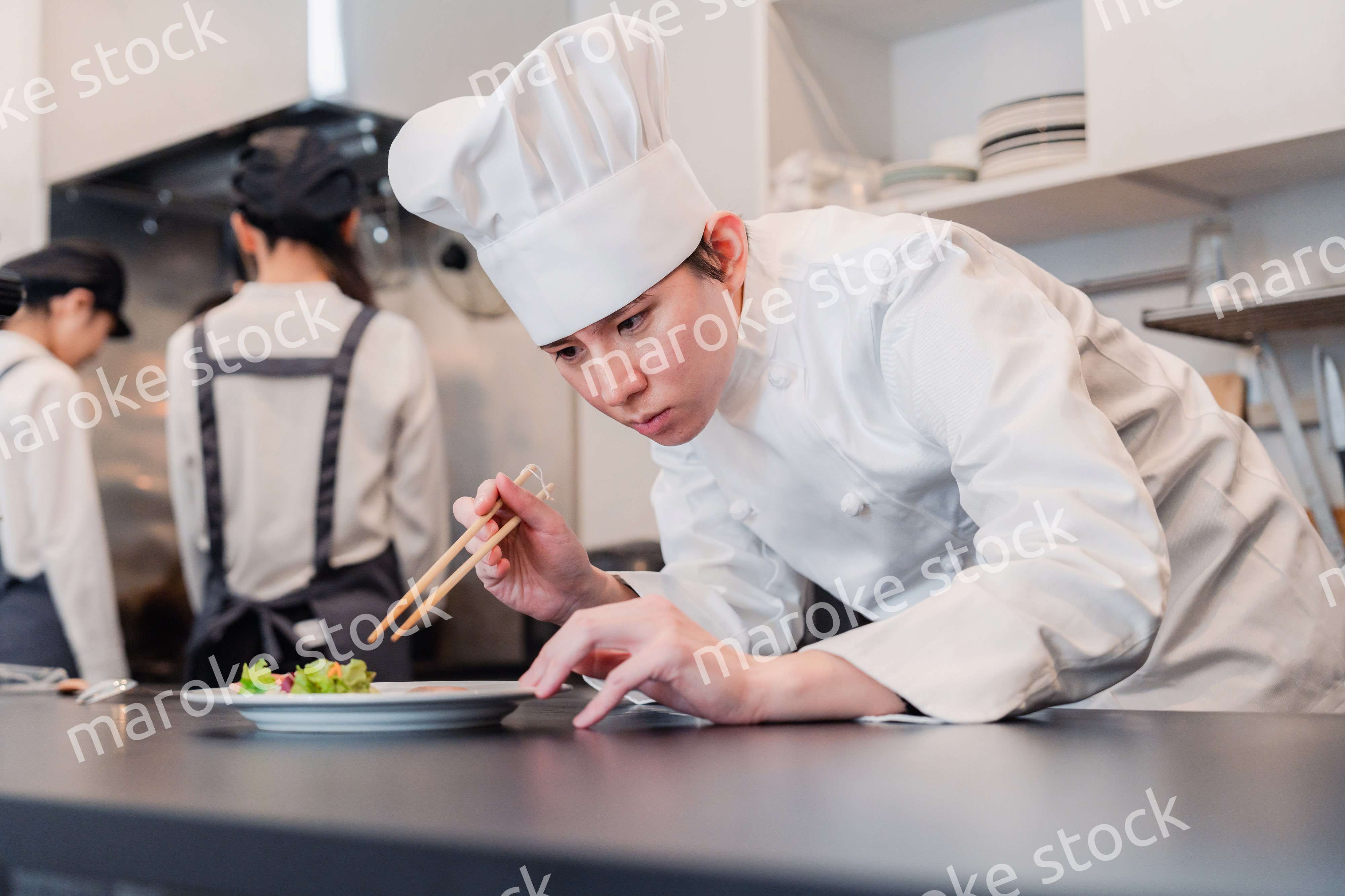 厨房で盛り付けをする男性シェフ