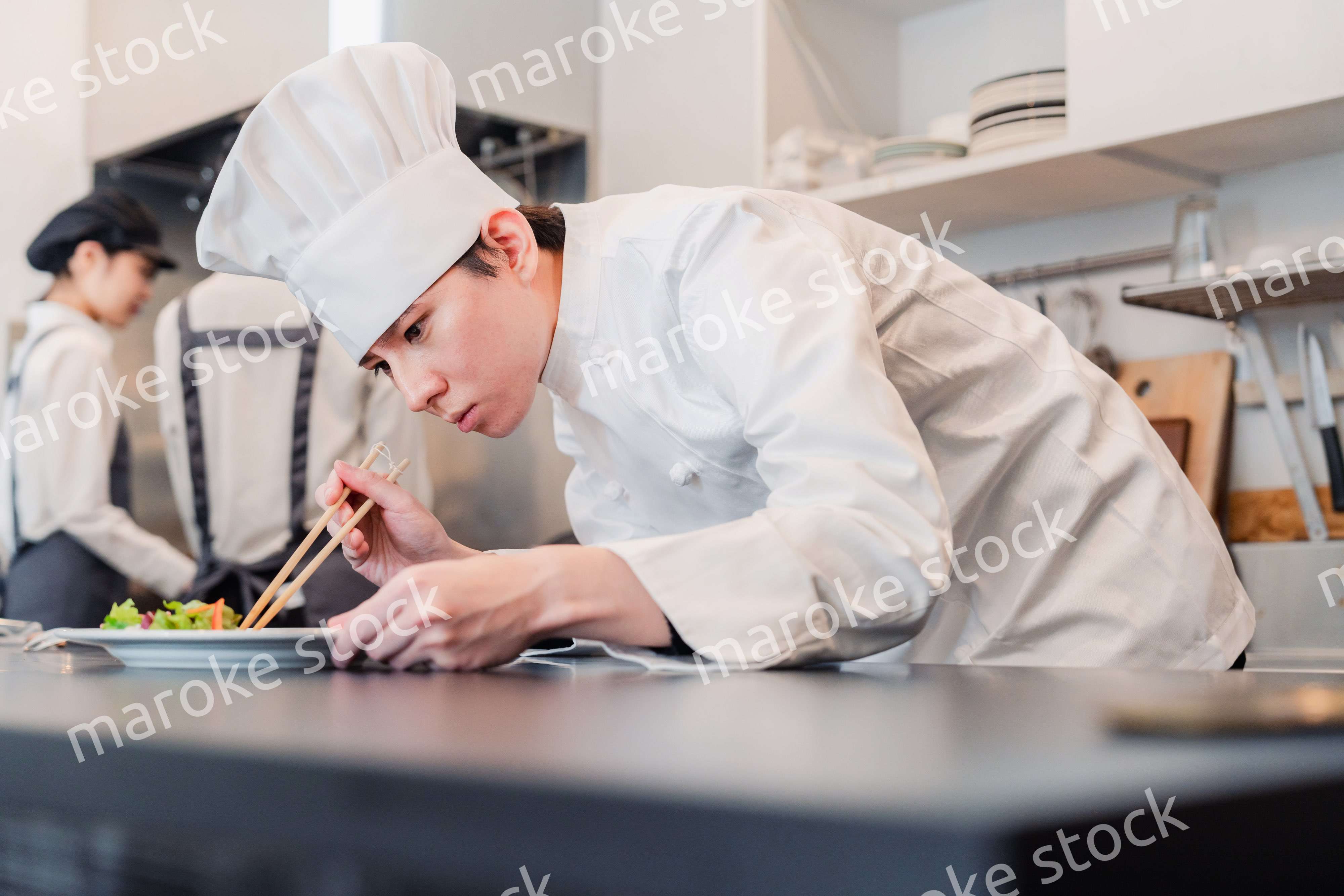 厨房で盛り付けをする男性シェフ