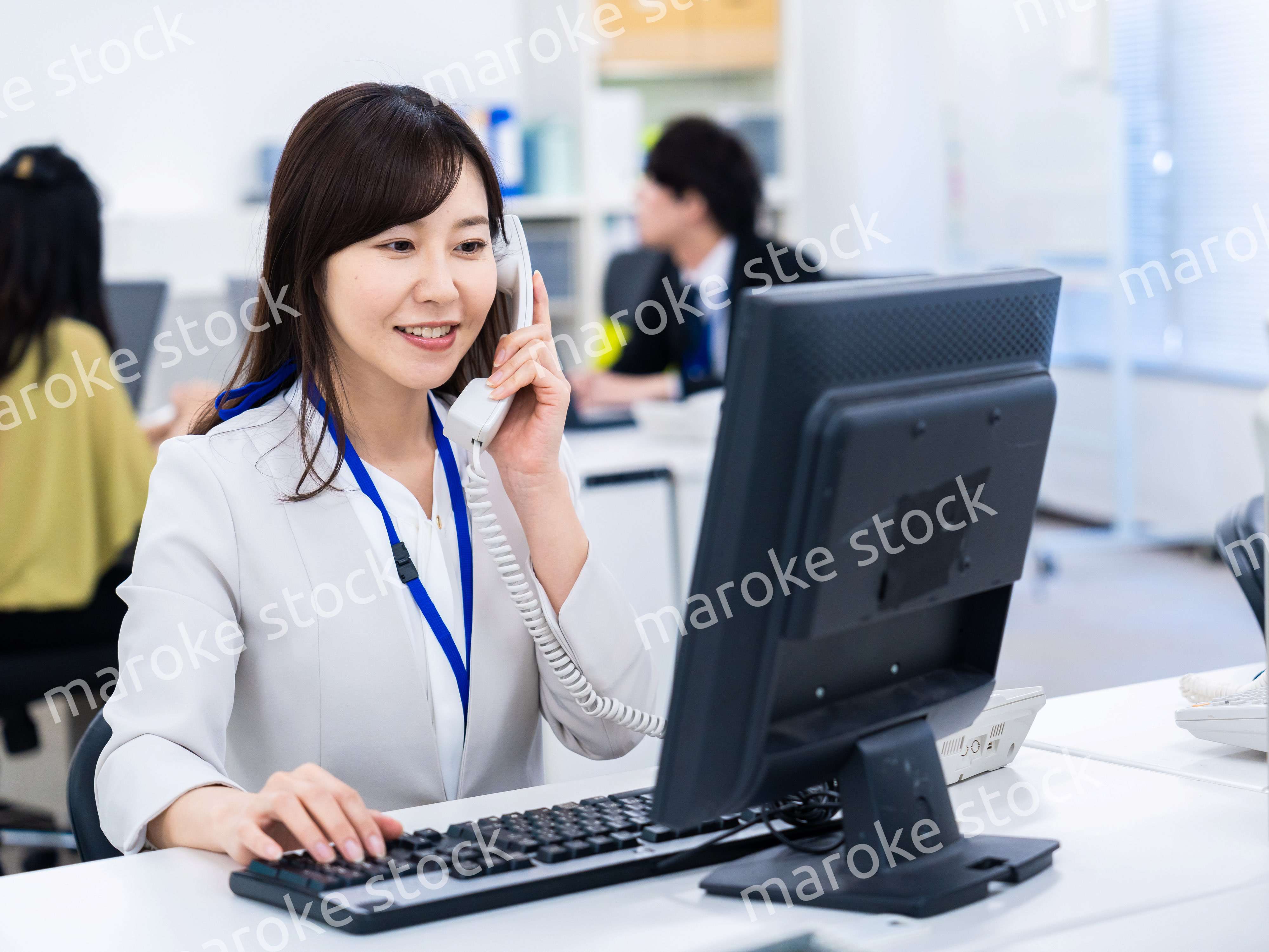 オフィスで固定電話を使う女性