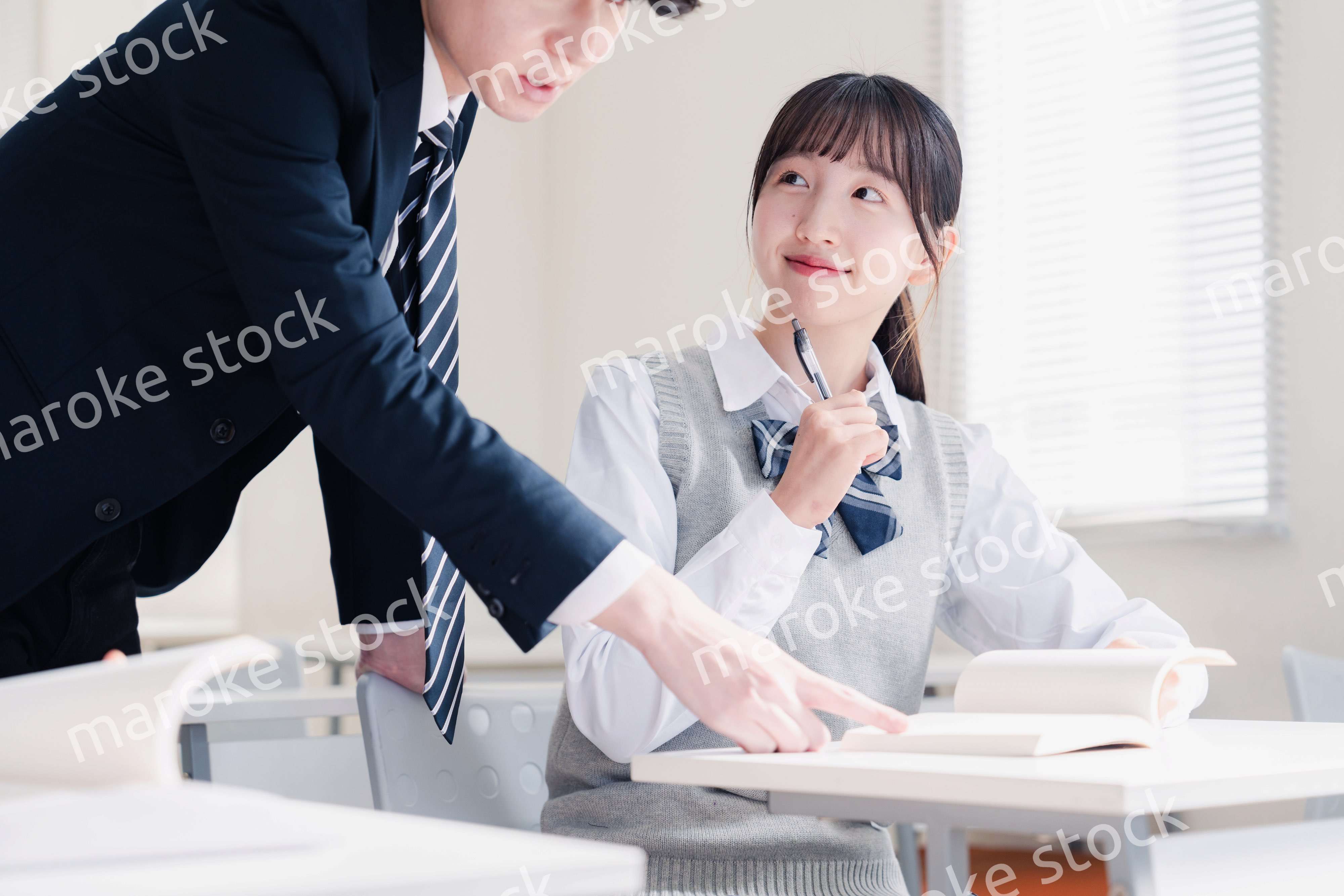 教室で先生に質問をする女子高生