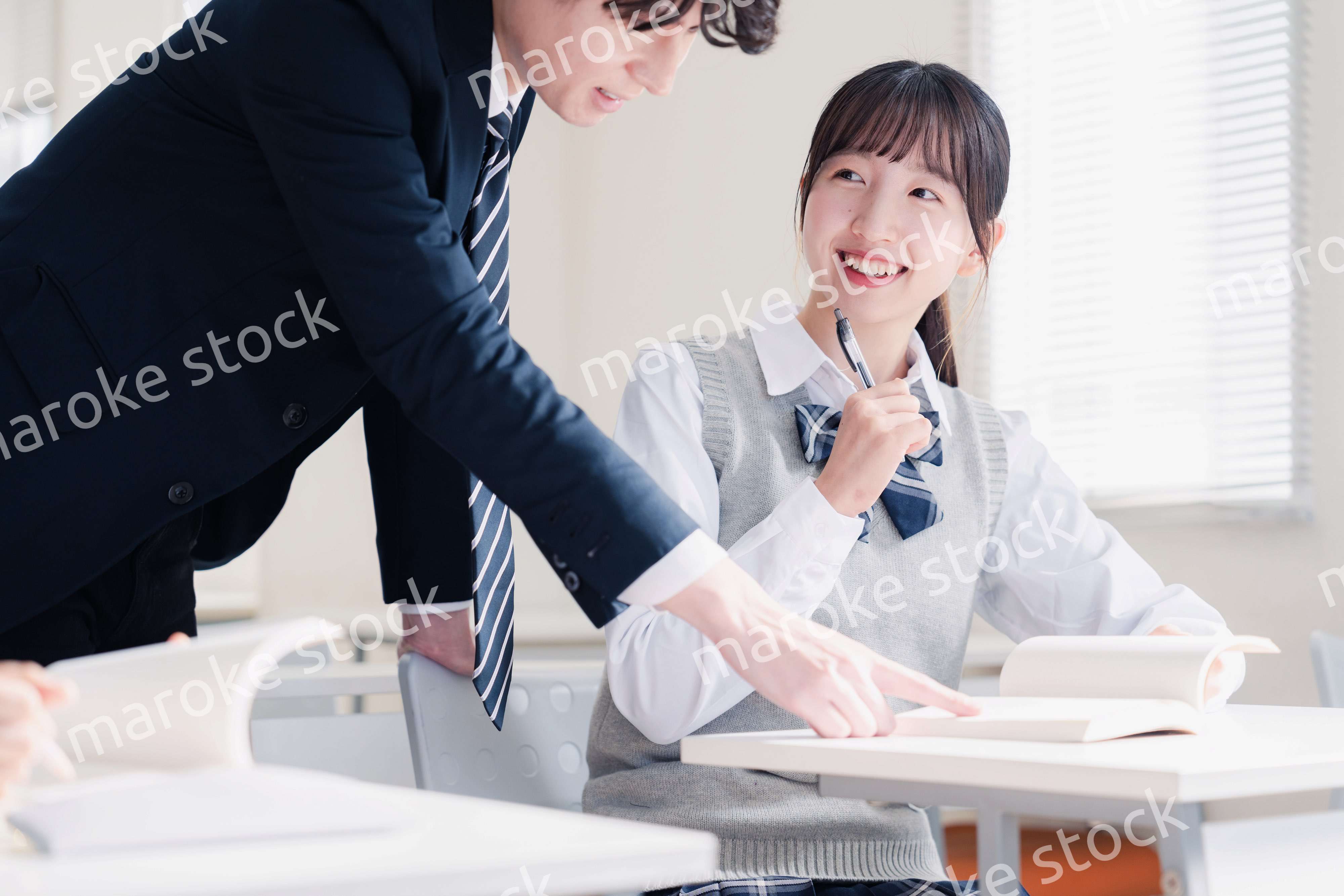 教室で先生に質問をする女子高生