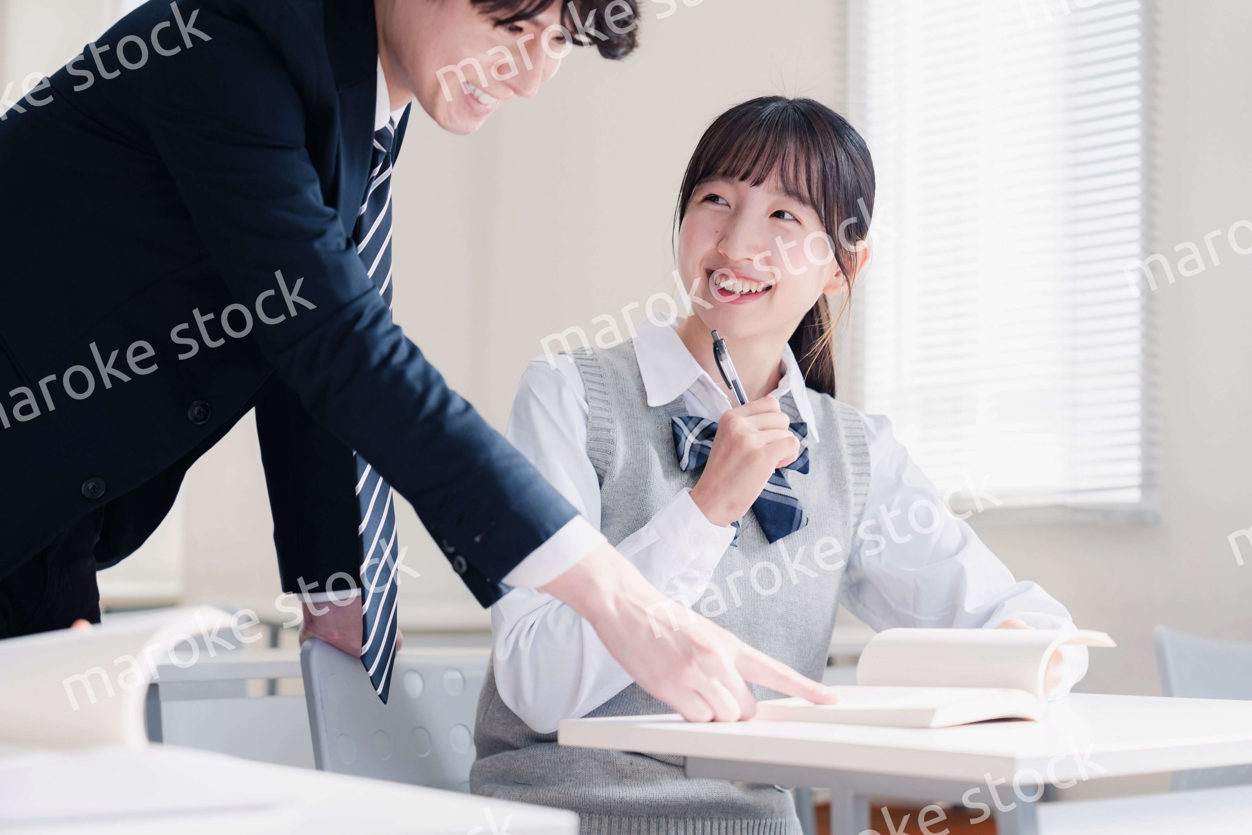 教室で先生に質問をする女子高生