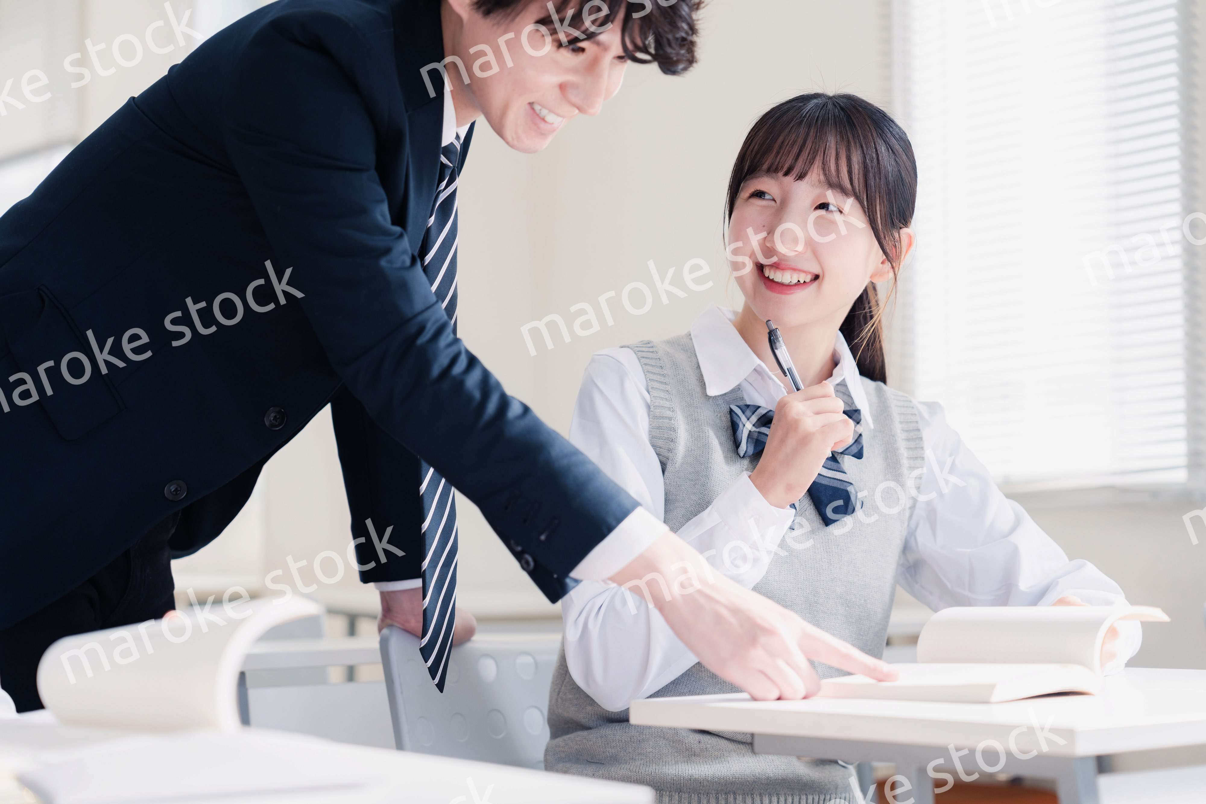 教室で先生に質問をする女子高生