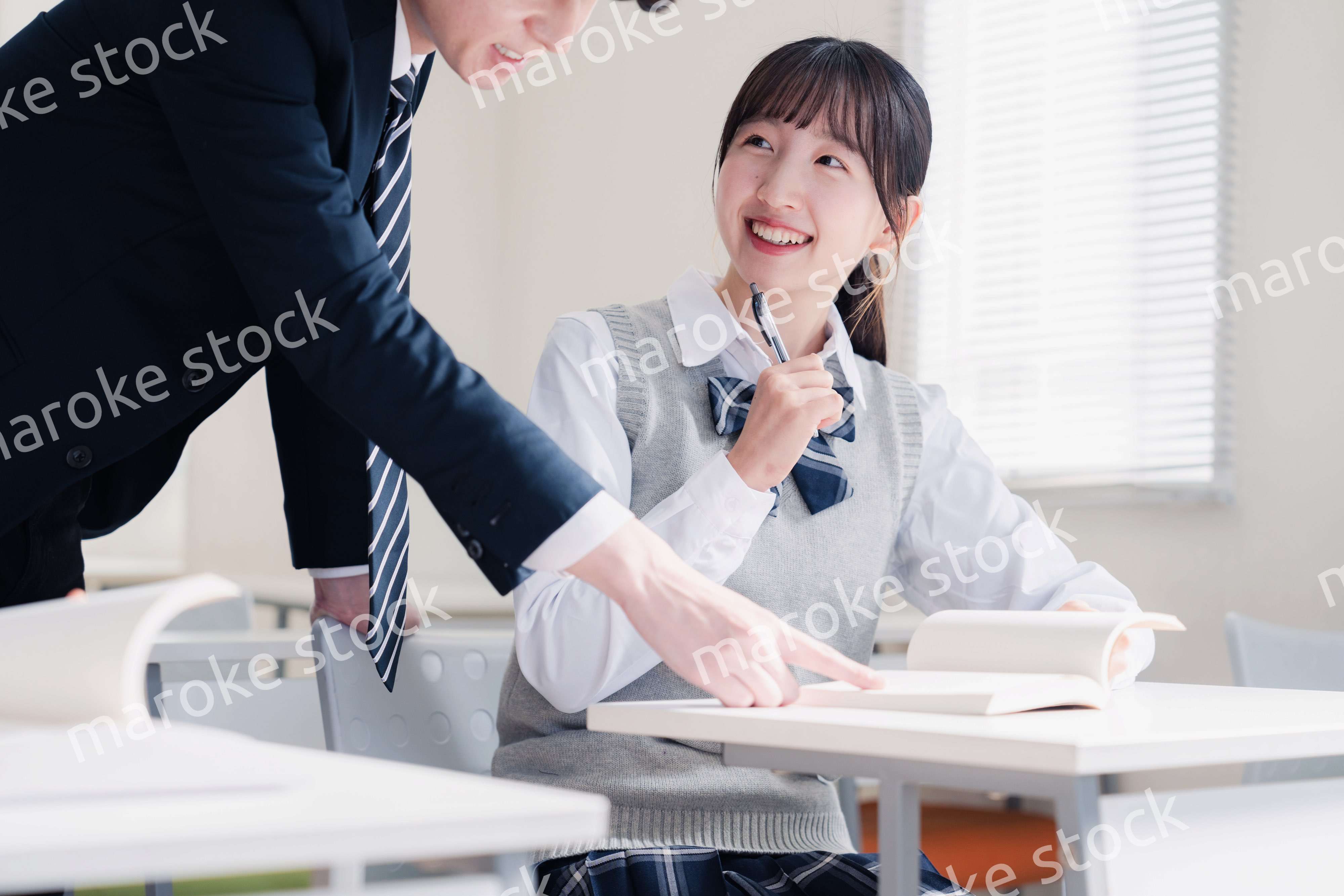 教室で先生に質問をする女子高生