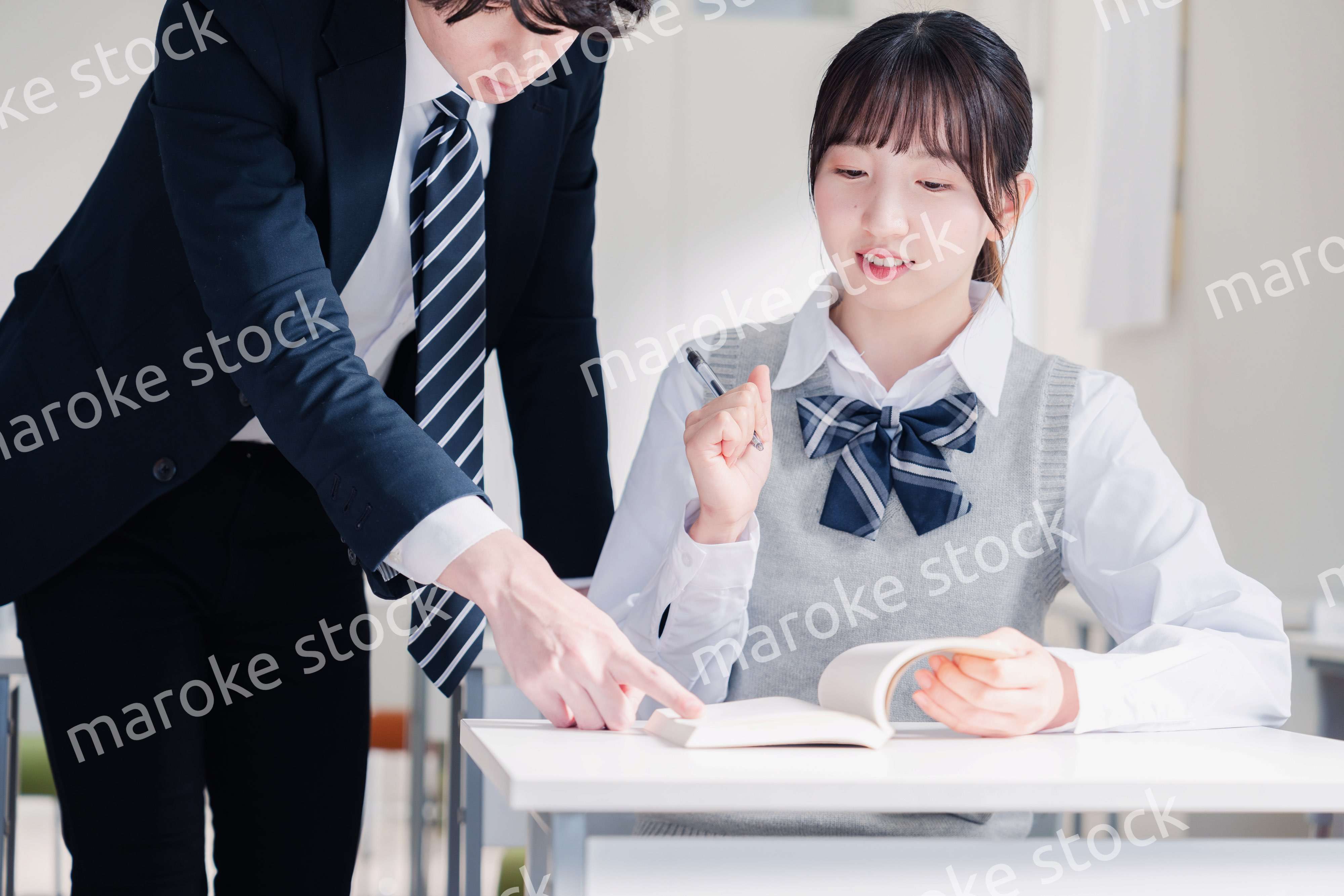 教室で先生に質問をする女子高生