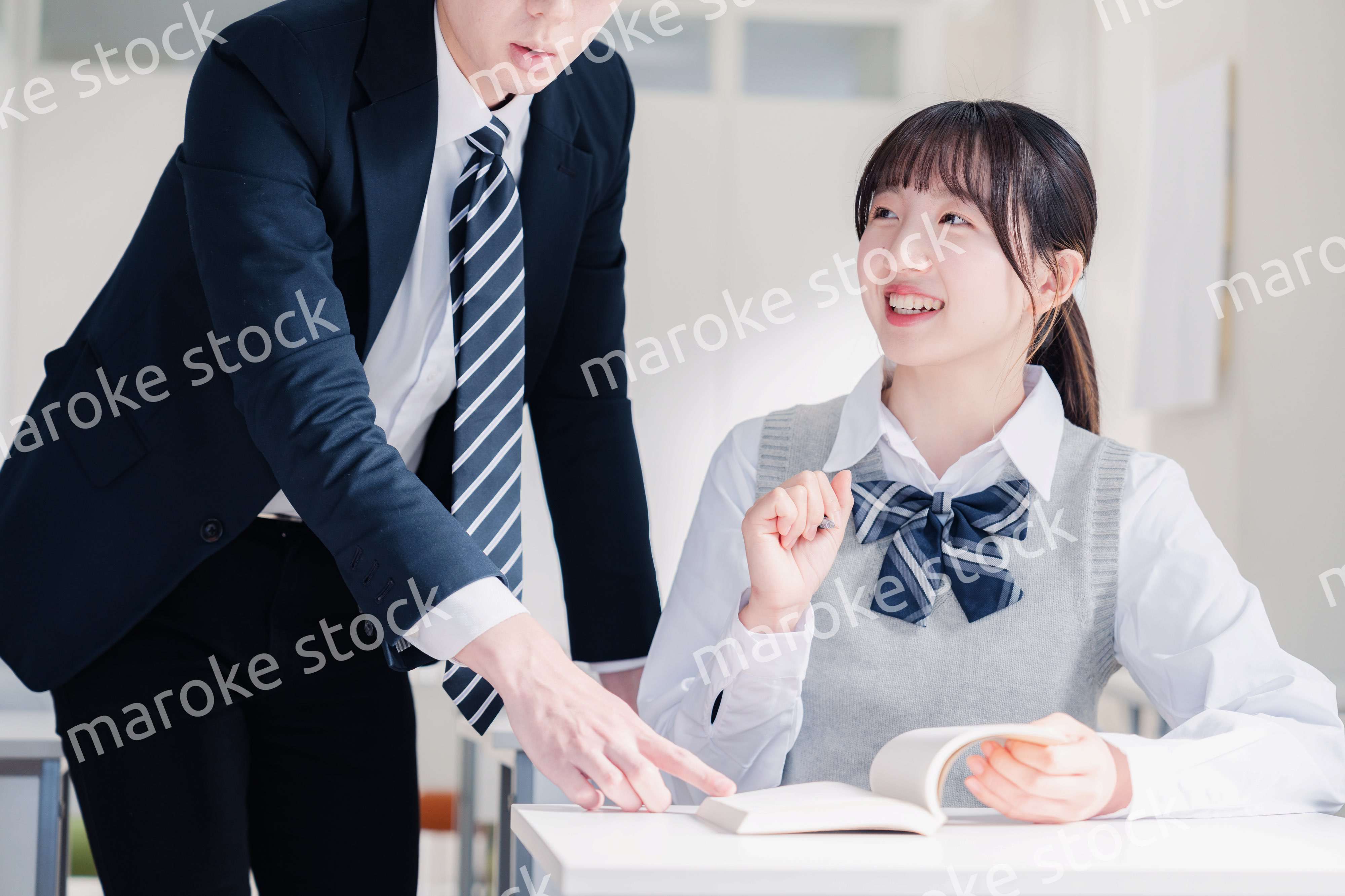 教室で先生に質問をする女子高生