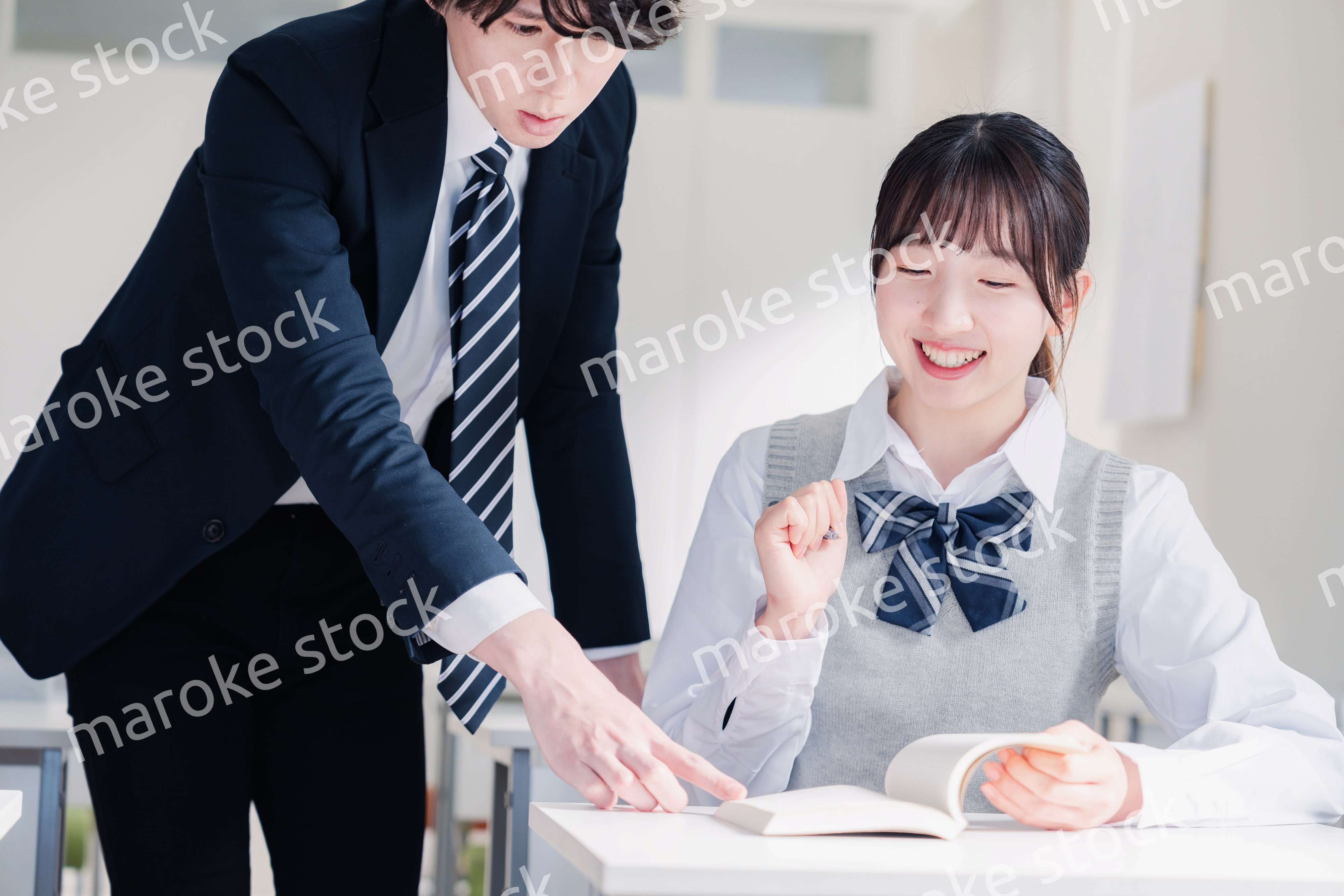 教室で先生に質問をする女子高生