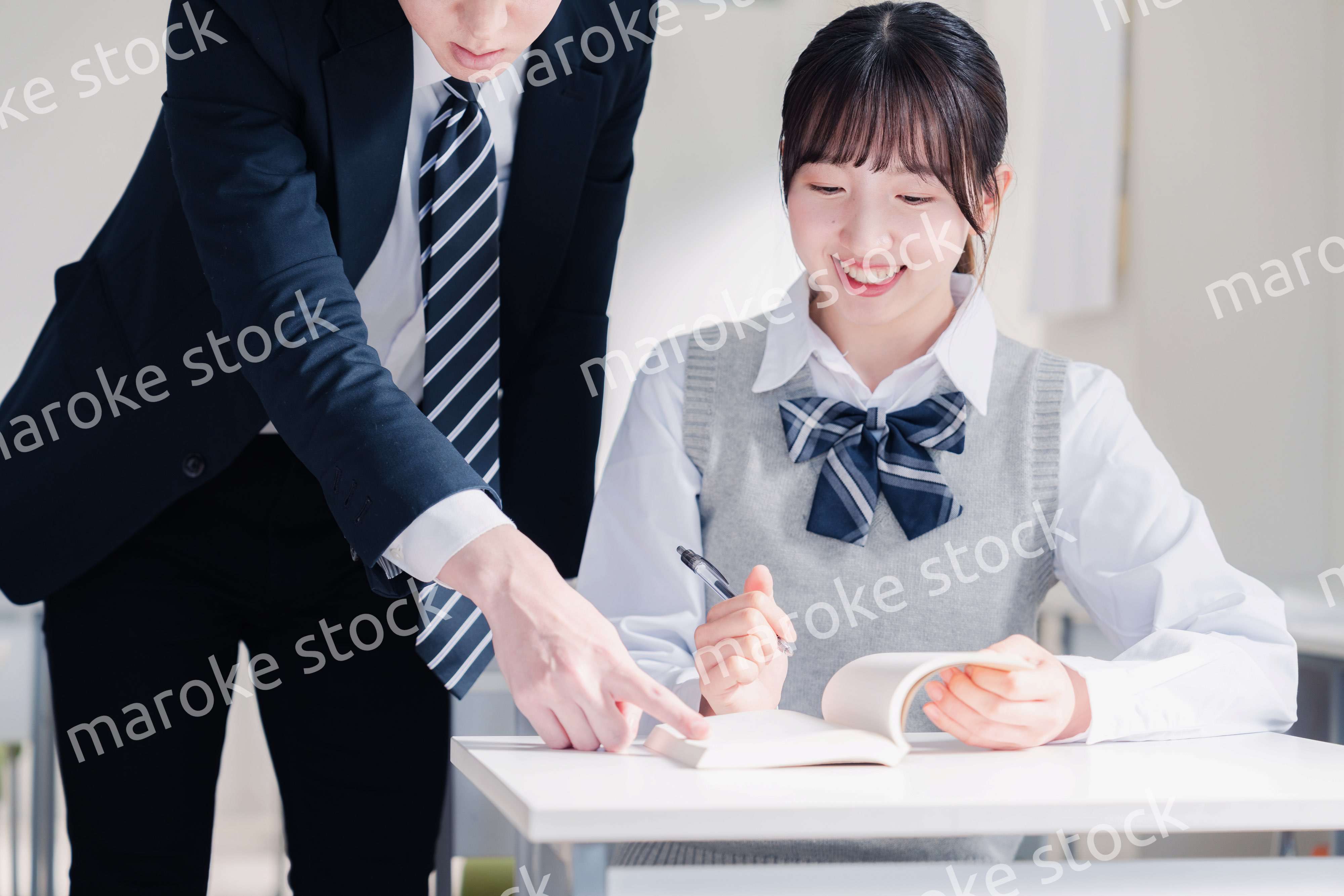 教室で先生に質問をする女子高生