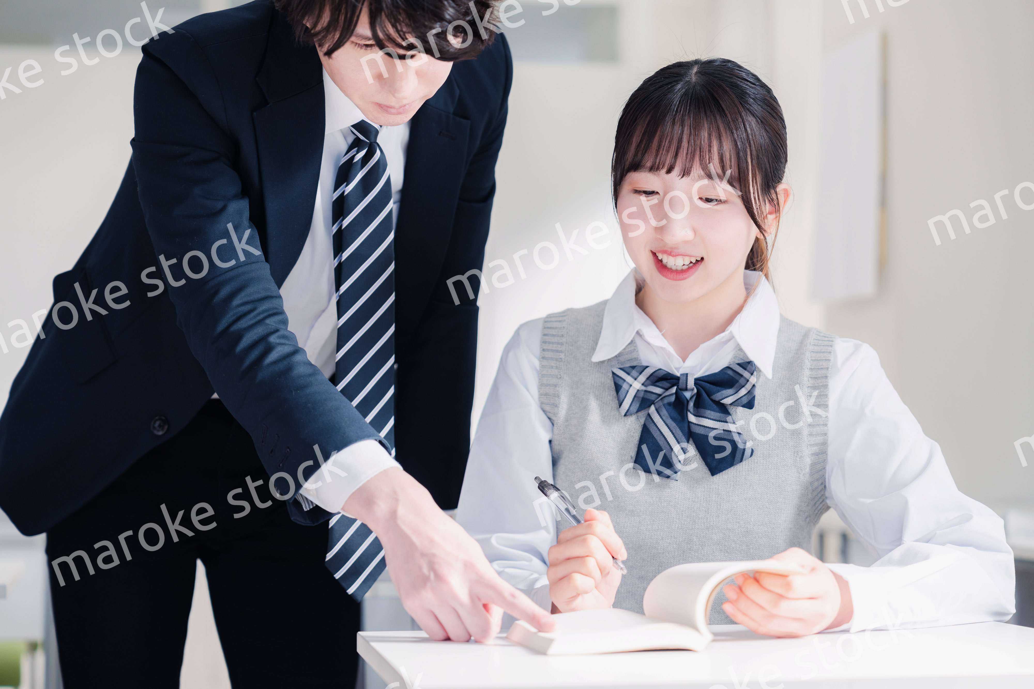 教室で先生に質問をする女子高生