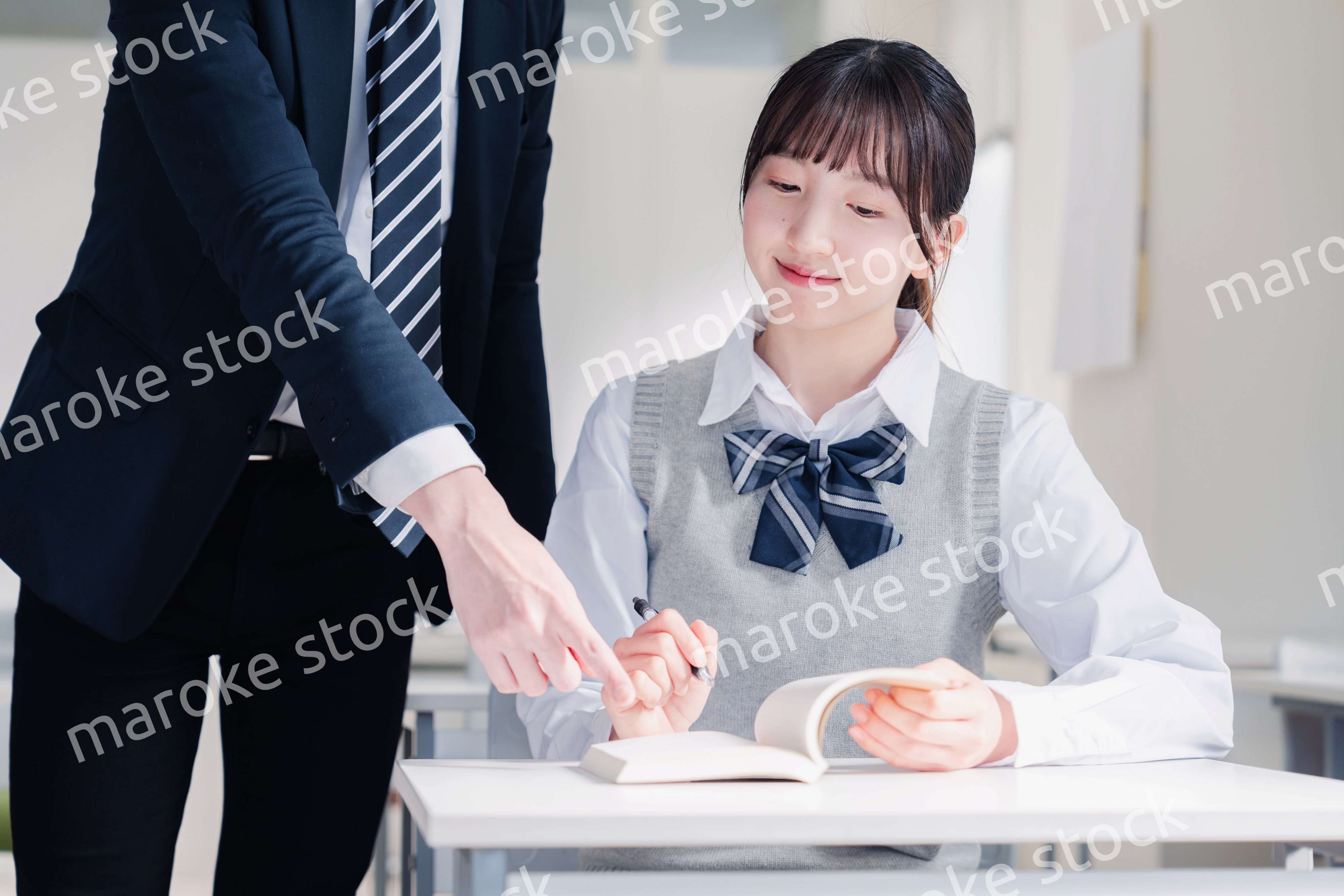 教室で先生に質問をする女子高生